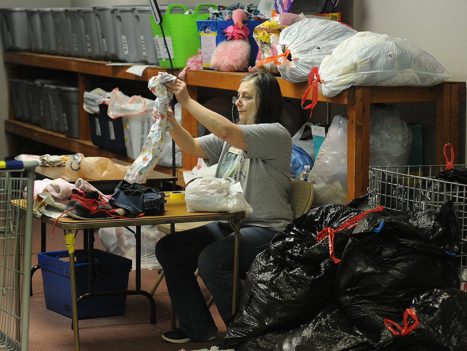 Tina Dells goes through numerous bags of donations to inspect each item at Hannah's Treasure Chest in Centerville Thursday, Jan. 25, 2024. The nonprofit has outgrown its space there and plans to relocate to a much larger Miamisburg building it purchased this month for nearly $1.7 million. MARSHALL GORBY/STAFF