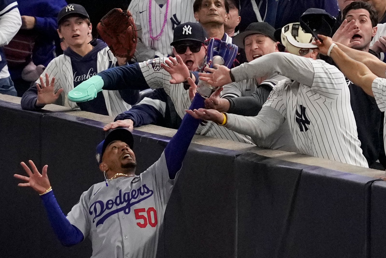 Fans interfere with a foul ball caught by Los Angeles Dodgers right fielder Mookie Betts during the first inning in Game 4 of the baseball World Series against the New York Yankees, Tuesday, Oct. 29, 2024, in New York. (AP Photo/Ashley Landis)