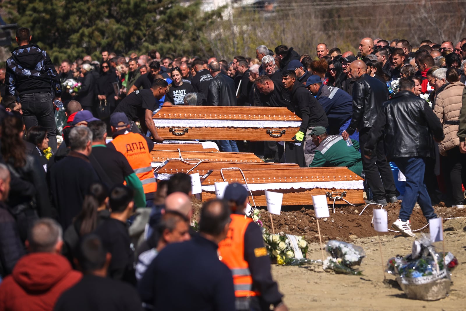 Coffins are placed next to the graves as people gather at a cemetery for the funeral ceremony of the victims of a massive nightclub fire in the town of Kocani, North Macedonia, Thursday, March 20, 2025. (AP Photo/Armin Durgut)