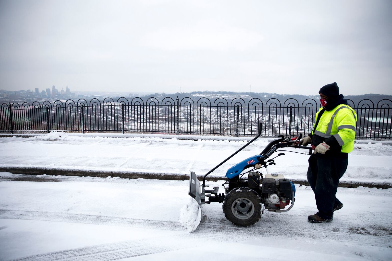 Cincinnati City Parks worker Kevin Manuel clears snow off the parking area at Mt. Echo Park in Cincinnati, Ohio, on Monday, Feb. 1, 2021.  (Albert Cesare/The Cincinnati Enquirer via AP)