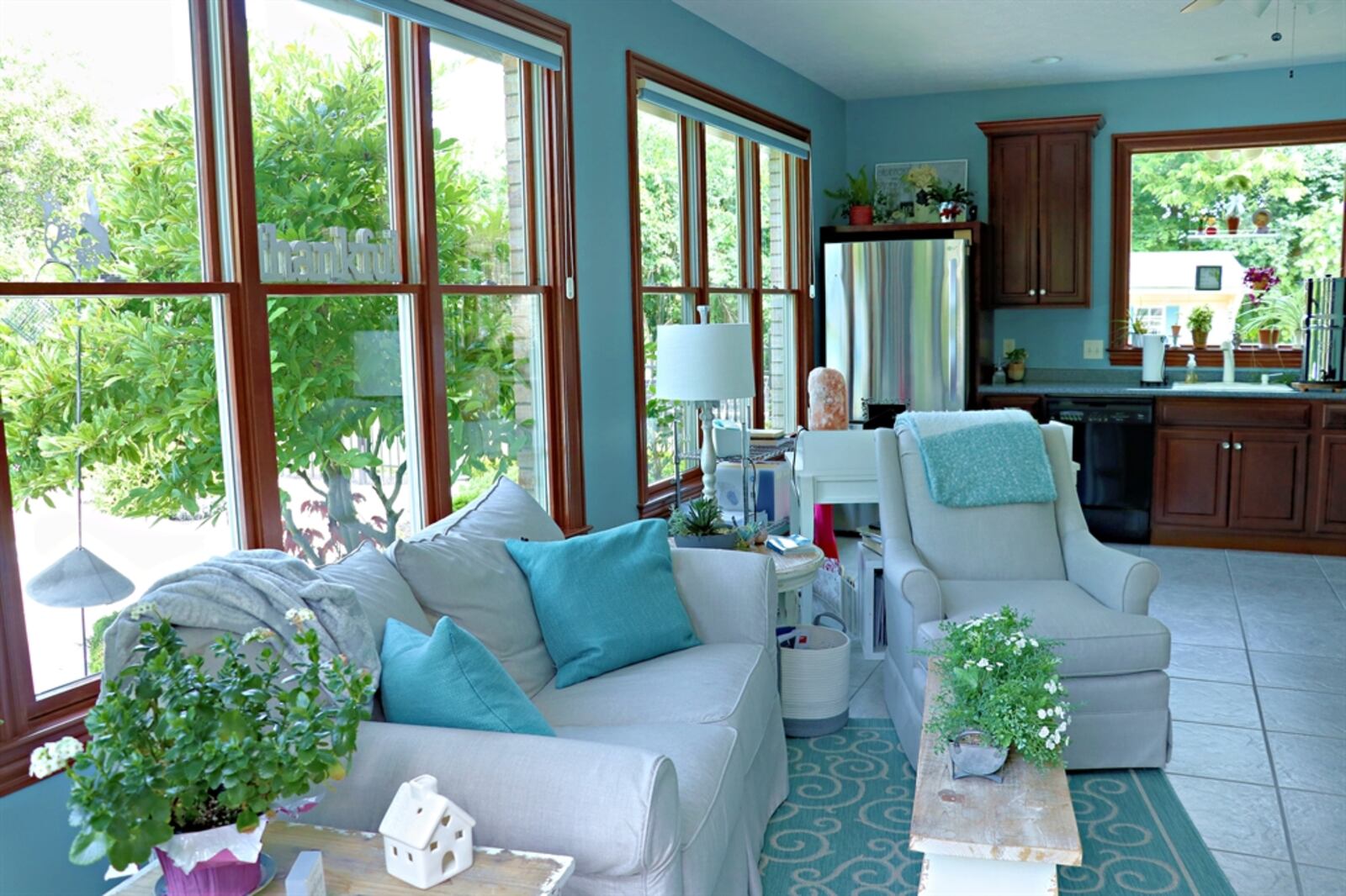 Wide French doors open from the breakfast room out to a four-season sunroom with walls of windows and ceramic-tile flooring.