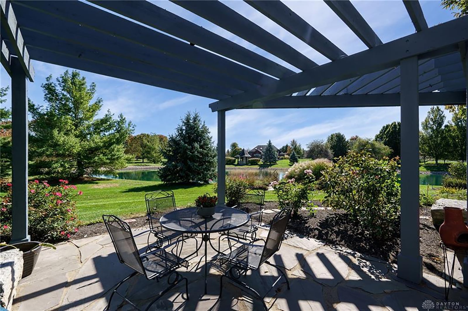 The rear of the home has a flagstone paver patio with wood pergola overlooking the pond.