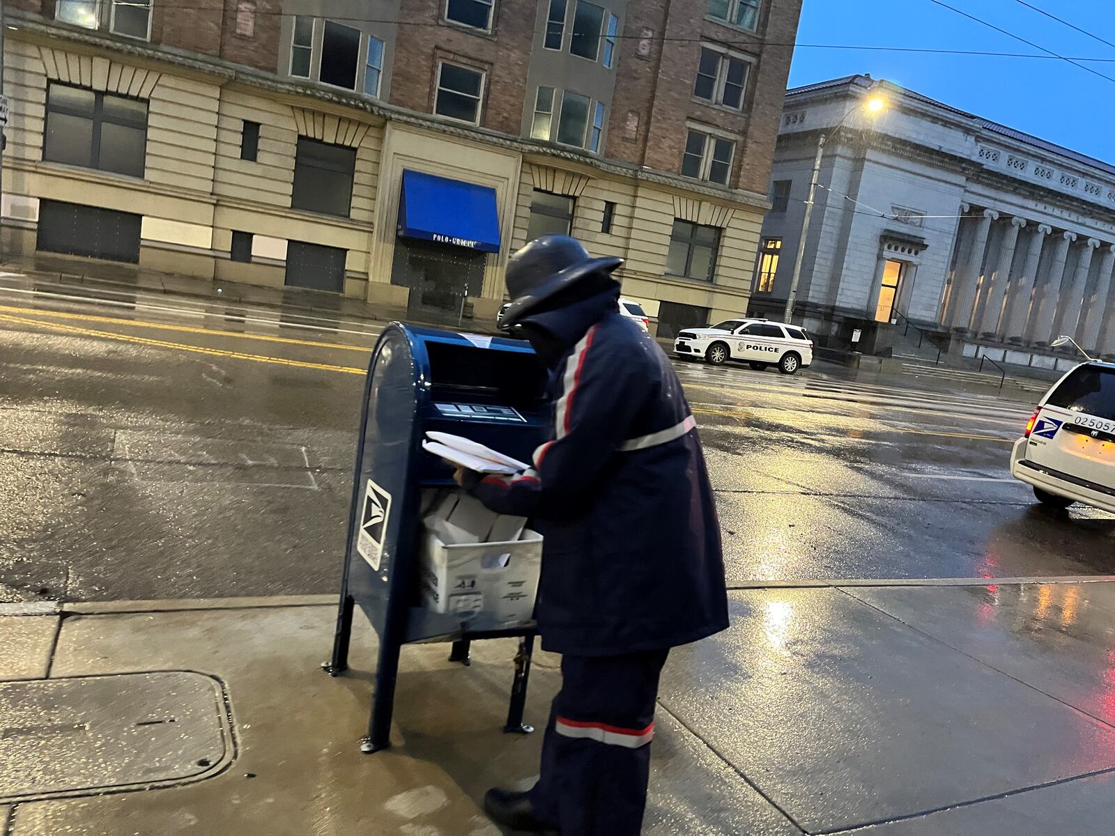 A U.S. postal worker picks up mail from a box in front of City Hall in downtown Dayton. The U.S. Postal Service is hiring city carrier assistants to work at the Dayton Main Post Office. CORNELIUS FROLIK / STAFF