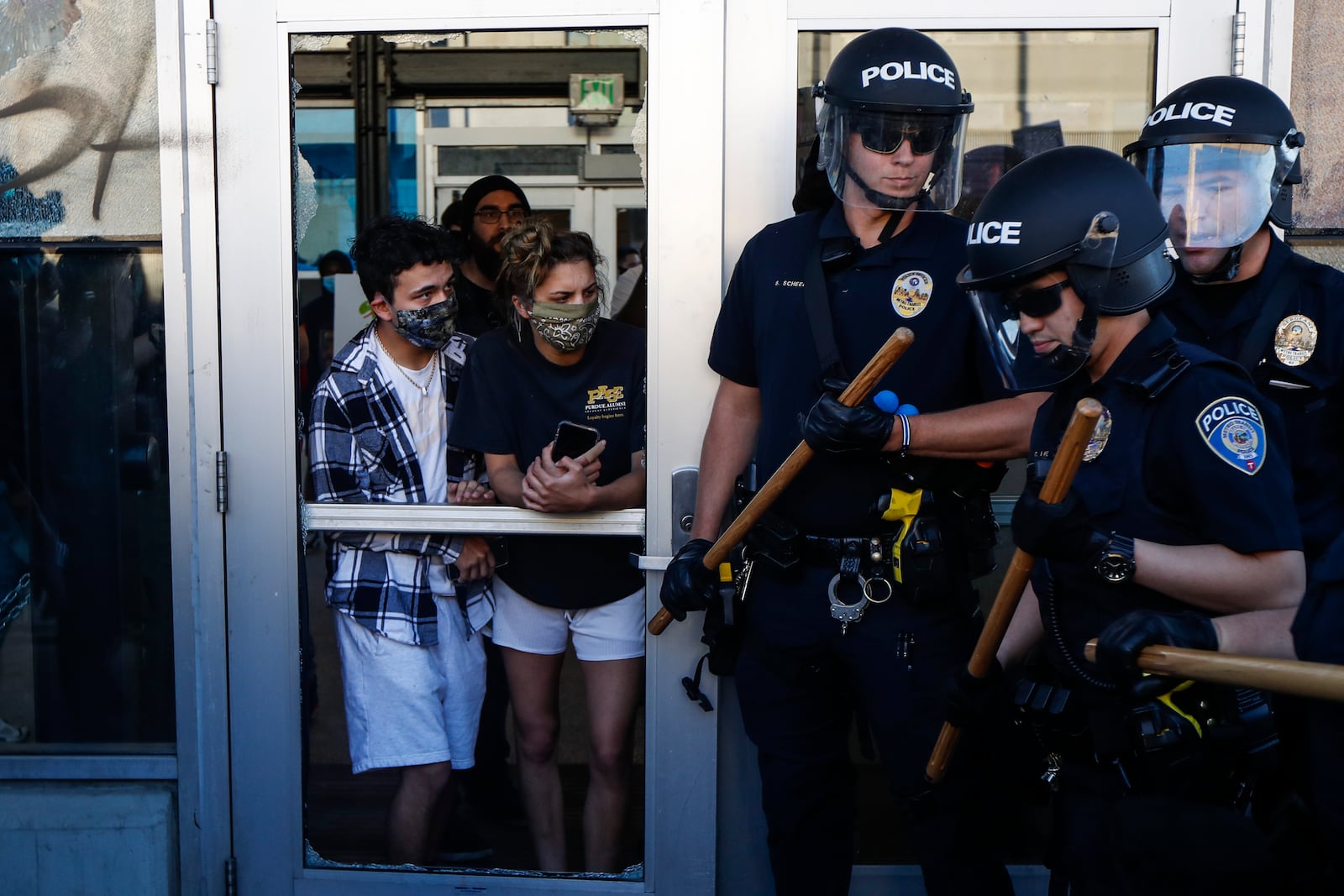 FILE - In this May 29, 2020, file photo, protesters watch police as they fall back to a defendable position during a skirmish at the intersection of East Lake Street and Hiawatha in St. Paul, Minn. Nearly a year after sometimes violent protests for racial justice shook Minneapolis, the immigrant corridor is struggling to recover. Lake Street, which was the focus of much violence during the protests that followed George Floyd's death in police custody, has been a beacon for immigrants for more than a century. (AP Photo/John Minchillo)