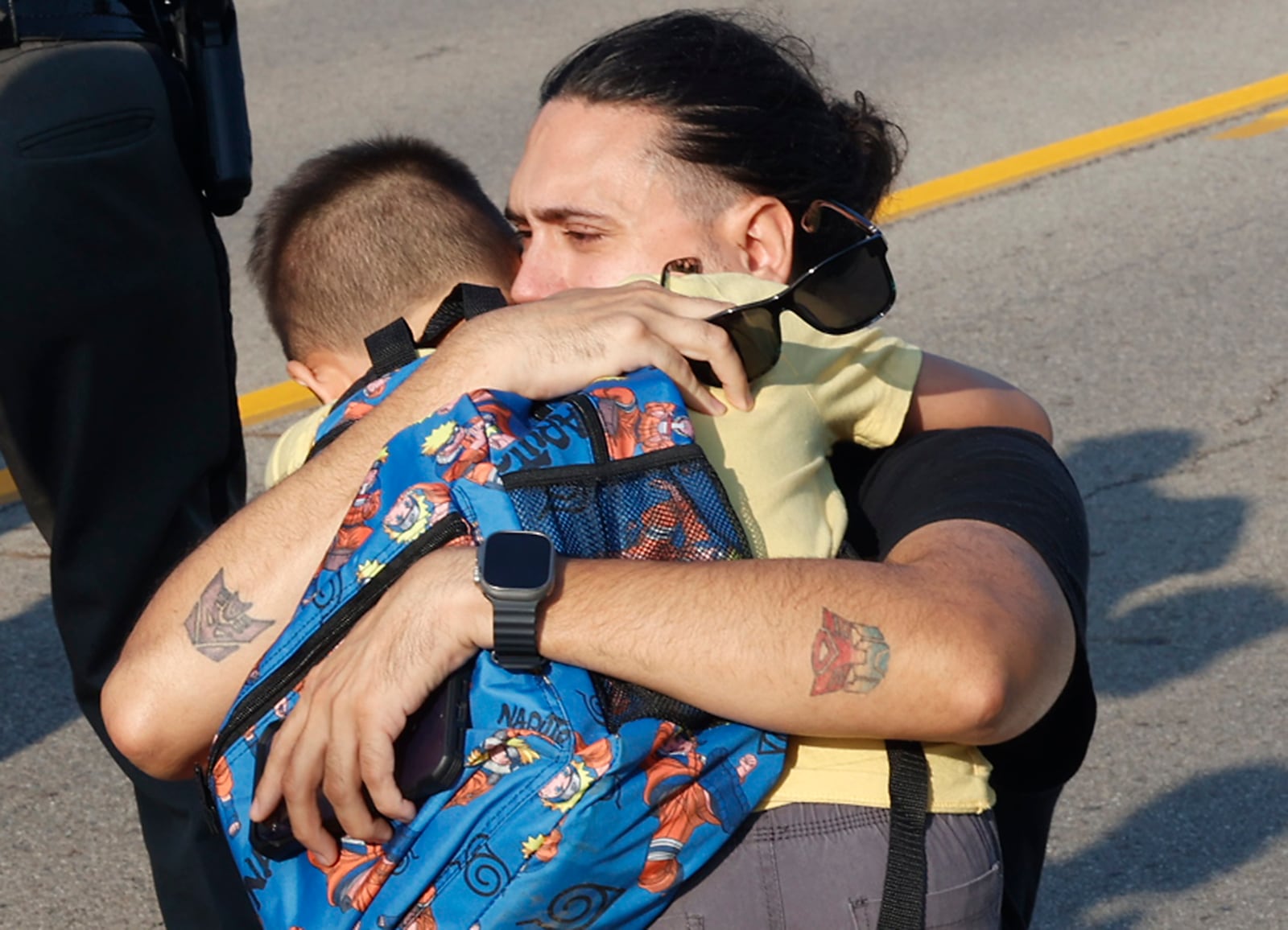 A father hugs his son after a Northwestern School District school bus crash in Springfield, Ohio, Tuesday, Aug. 22, 2023. (Bill Lackey/The Springfield News-Sun via AP)