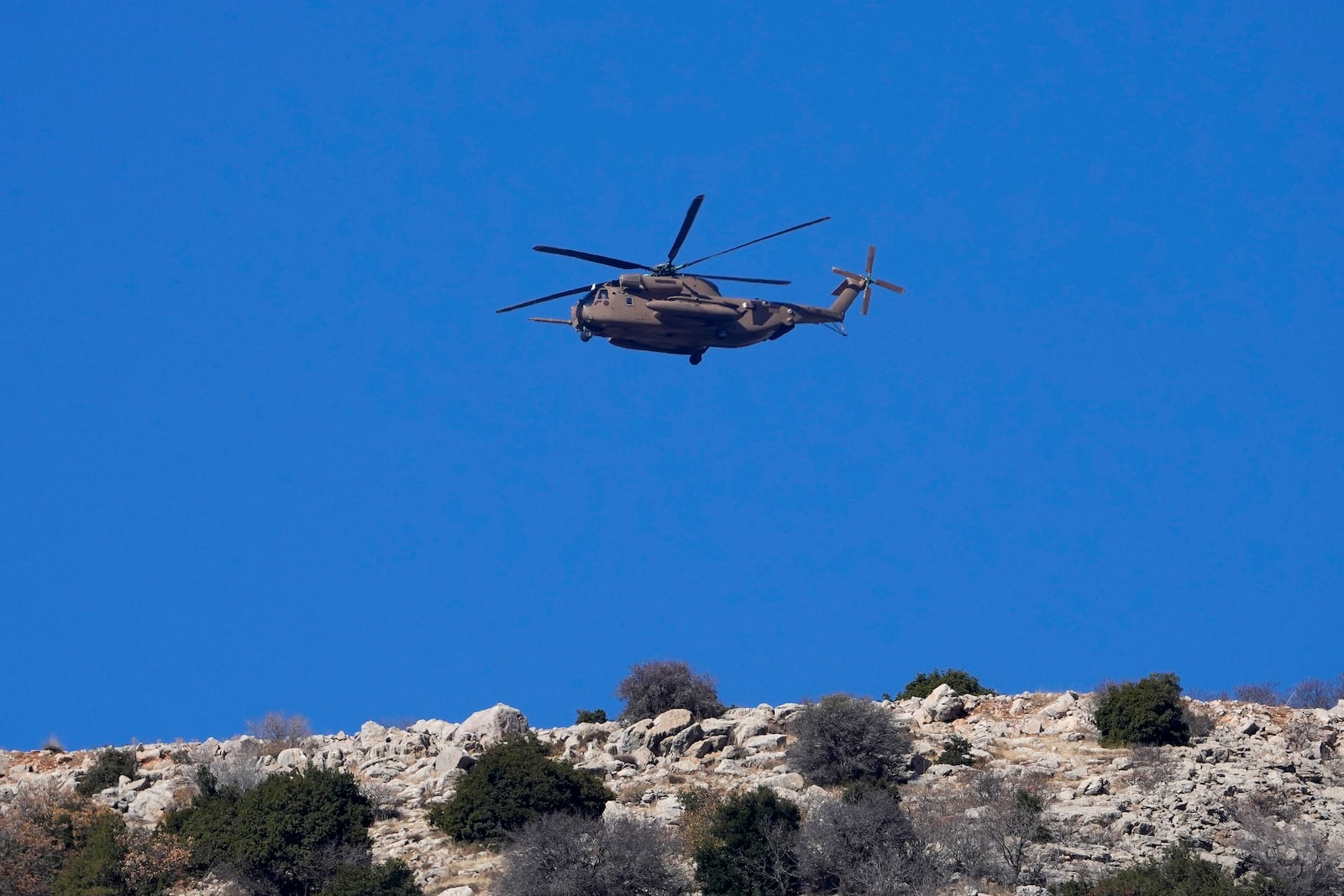 An Israeli Air Force Black Hawk helicopter flies over Mount Hermon near the so-called Alpha Line that separates the Israeli-controlled Golan Heights from Syria, viewed from the town of Majdal Shams, Tuesday, Dec. 17, 2024. (AP Photo/Matias Delacroix)