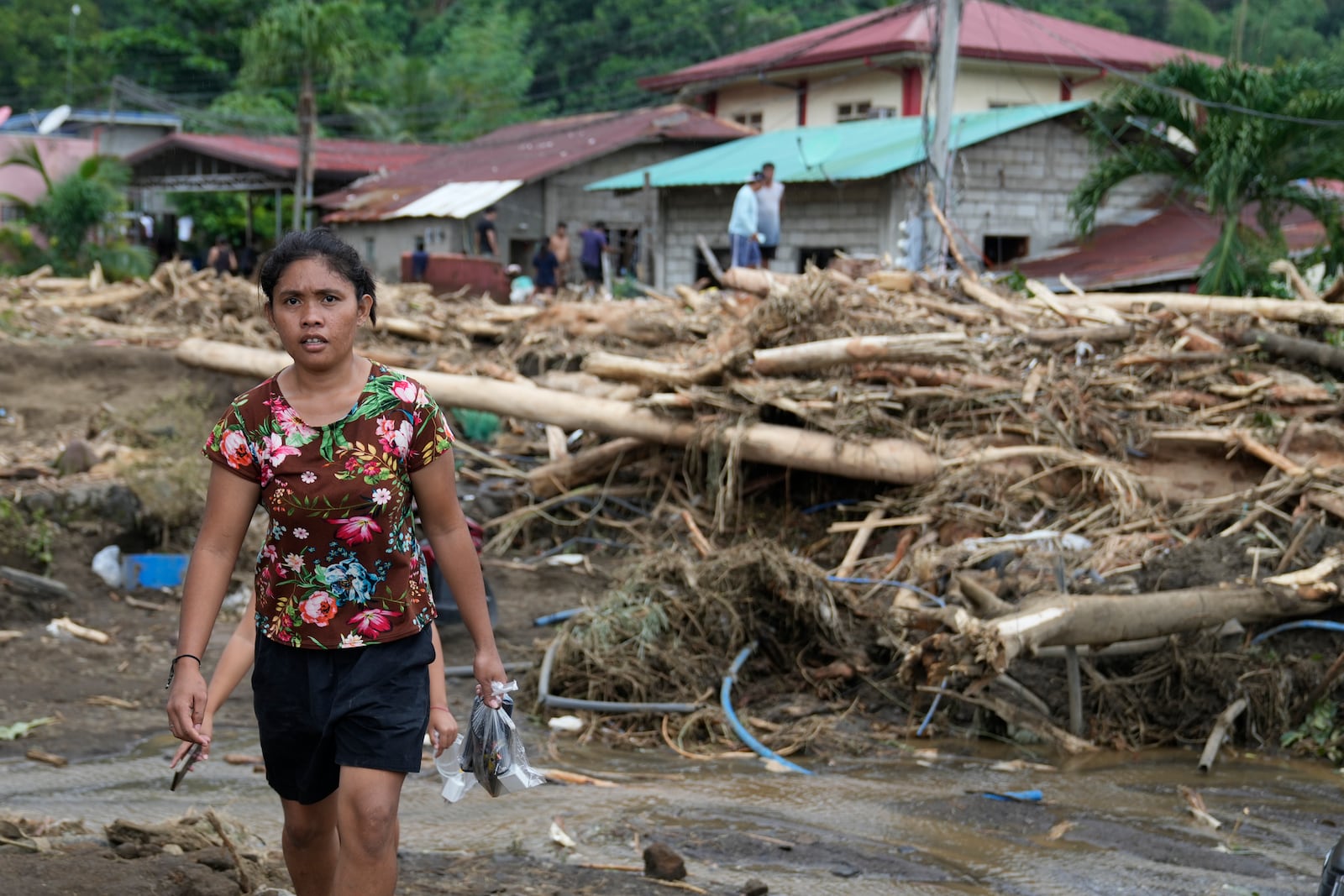 A resident passes by toppled trees after a landslide triggered by Tropical Storm Trami recently struck Talisay, Batangas province, Philippines, Saturday, Oct. 26, 2024. (AP Photo/Aaron Favila)