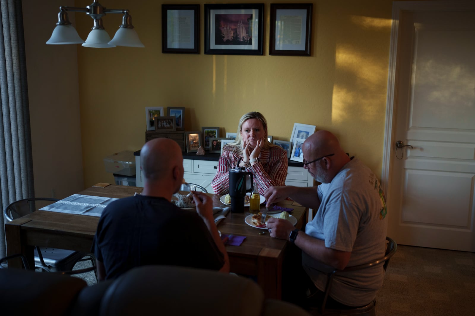 Cari-Ann Burgess, interim Registrar of Voters for Washoe County, Nev., center, eats dinner with her husband Shane Burgess, right, at their home Friday, Sept. 20, 2024, in Reno, Nev. (AP Photo/John Locher)