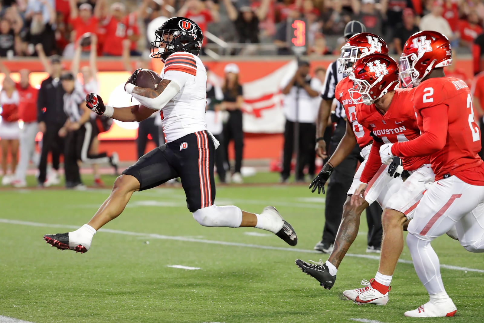 Utah running back Micah Bernard, left, leaps into the end zone to score in front of Houston's Kentrell Webb, third from right, Michael Batton, second from right, and A.J. Haulcy (2) during the second half of an NCAA college football game Saturday, Oct. 26, 2024, in Houston. (AP Photo/Michael Wyke)