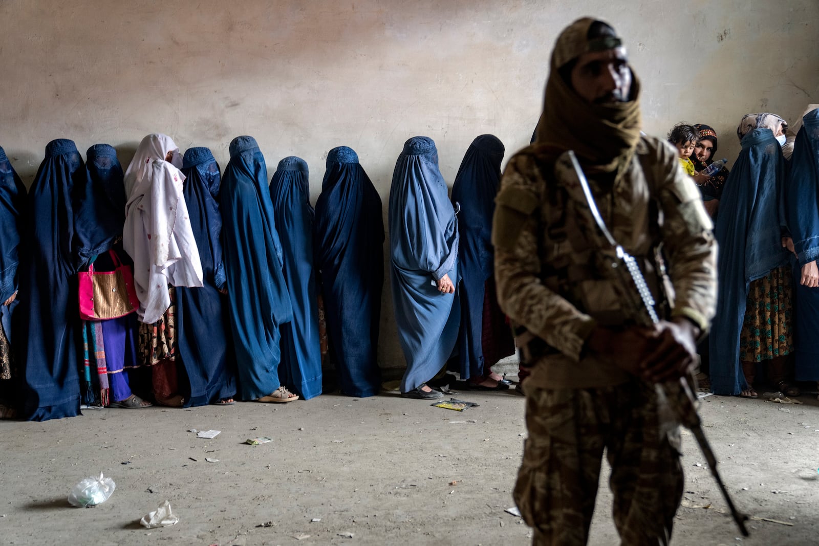 FILE - A Taliban fighter stands guard as women wait to receive food rations distributed by a humanitarian aid group in Kabul, Afghanistan, May 23, 2023. (AP Photo/Ebrahim Noroozi, File)