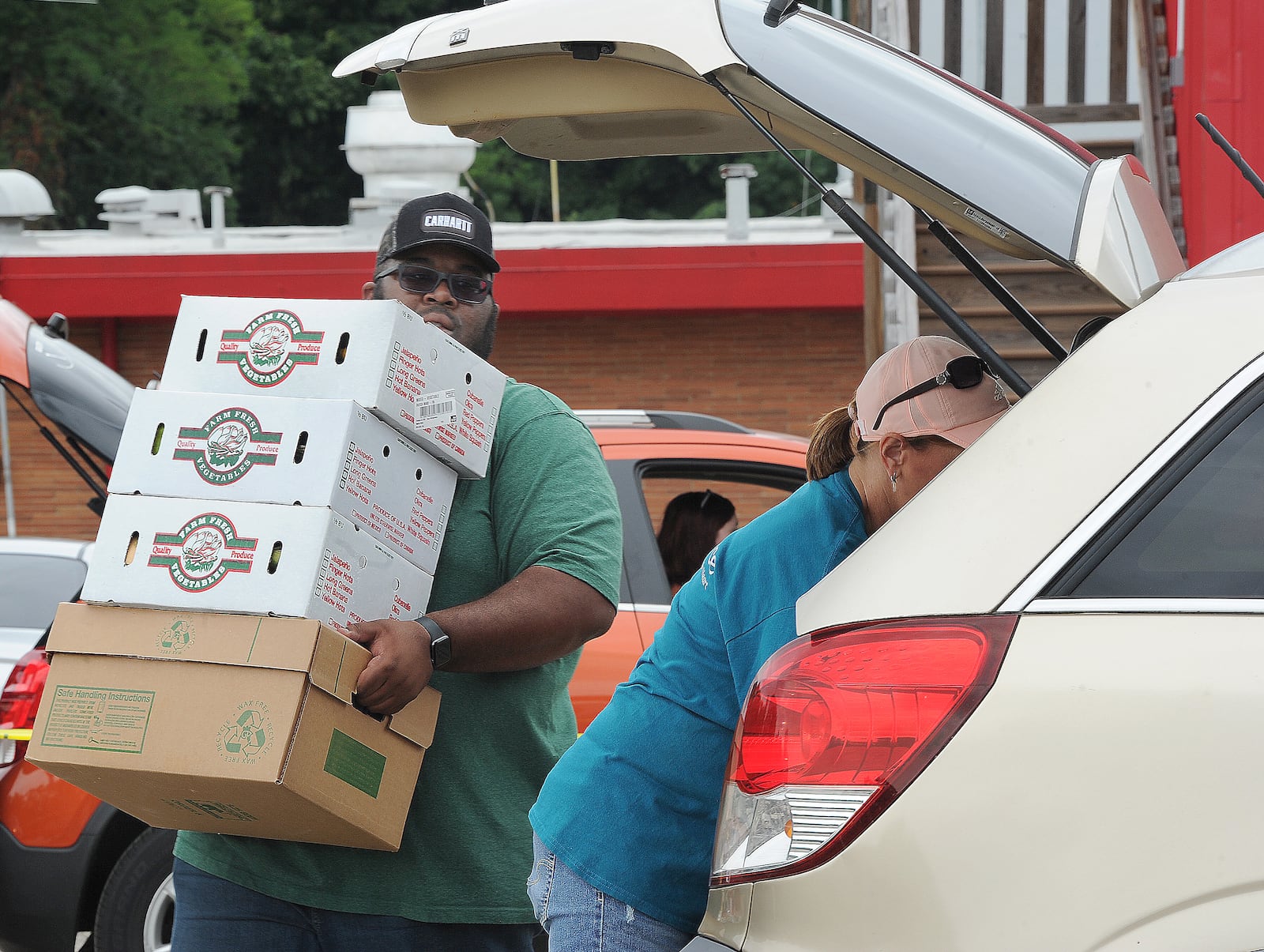 Aaron Fields loads boxes of food into a SUV Tuesday Aug. 16, 2021, during the mass drive-through food distribution at the Dixie Twin Drive-In hosted by The Foodbank. MARSHALL GORBY\STAFF