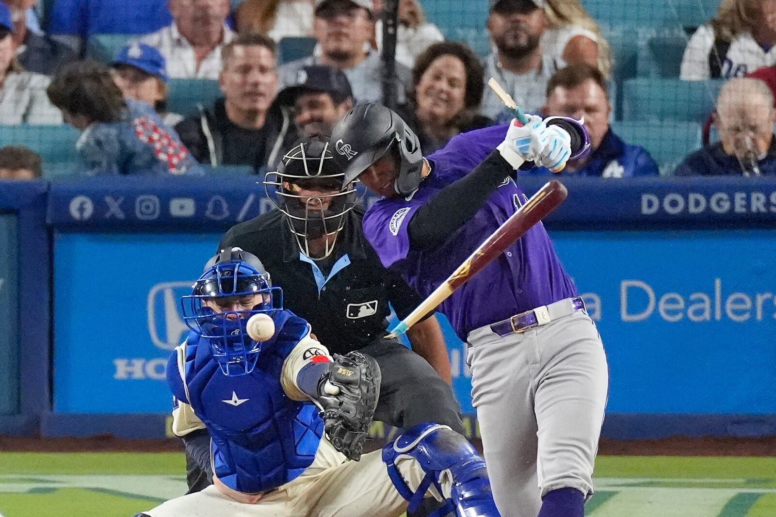 Colorado Rockies' Ezequiel Tovar, right, breaks his bat as he hits into a double play while Los Angeles Dodgers catcher Hunter Feduccial, left, and home plate umpire Jeremie Rehak watch during the seventh inning of a baseball game, Saturday, Sept. 21, 2024, in Los Angeles. (AP Photo/Mark J. Terrill)