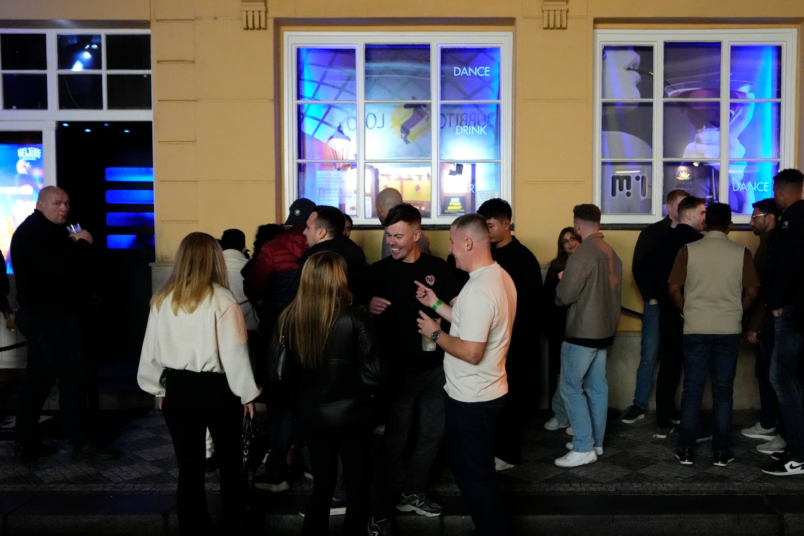 A group of tourists stand in line outside a bar as they attend a pub crawl tour in downtown Prague, Czech Republic, Thursday, Oct. 17, 2024. (AP Photo/Petr David Josek)