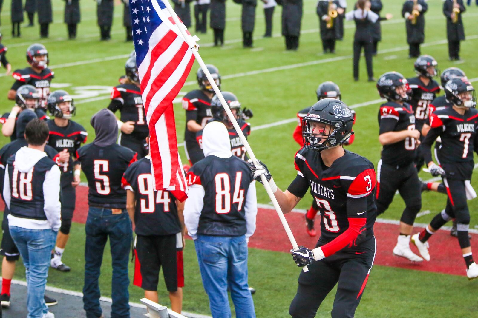 Franklin’s Kyle Rickard (3) waves the American flag as the team takes the field to play Edgewood on Friday night at Atrium Stadium in Franklin. GREG LYNCH/STAFF