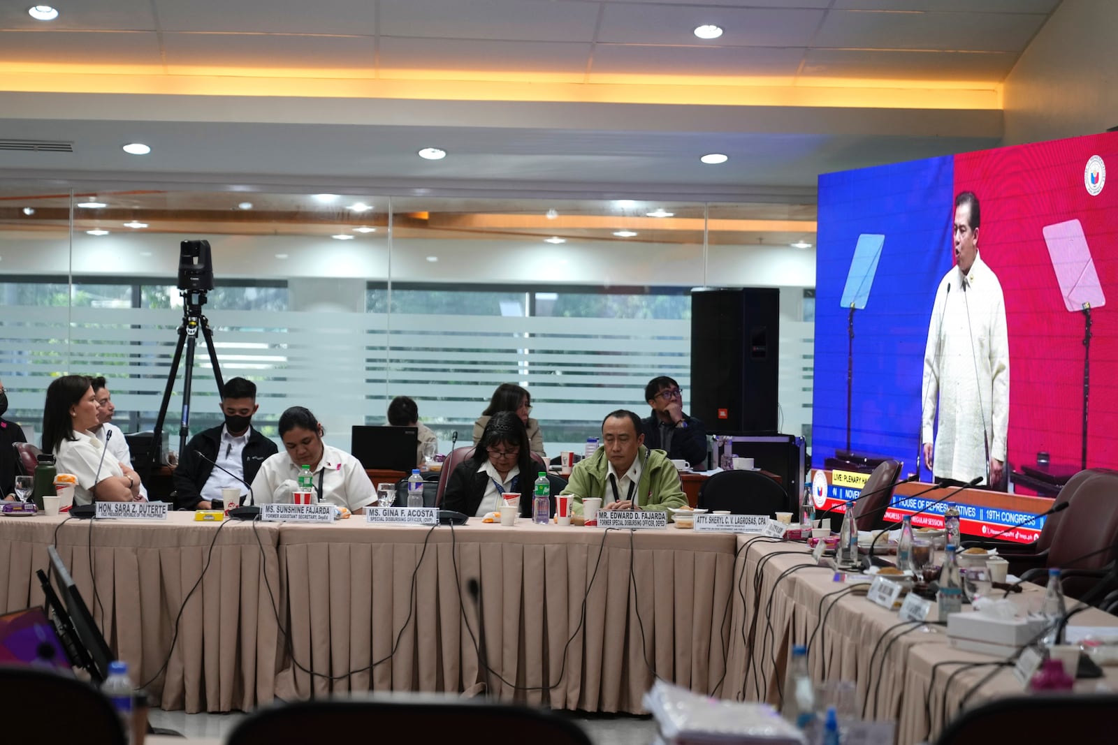 Philippine Vice President Sara Duterte, left seated, listens to House Speaker Martin Romualdez shown on an electronic board at the House of Representative in Quezon City, Philippines Monday, Nov. 25, 2024. (AP Photo/Aaron Favila)