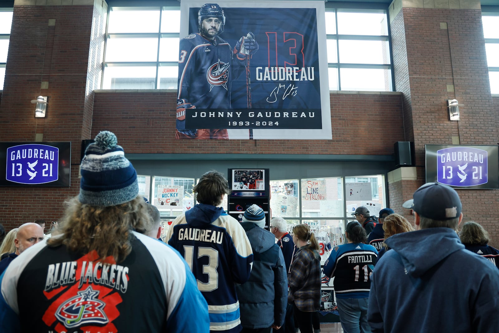 Fans look at a memorial of Columbus Blue Jackets' Johnny Gaudreau and his brother Matthew before the start of an NHL hockey game against the Florida Panthers. Tuesday, Oct. 15, 2024, in Columbus, Ohio. (AP Photo/Jay LaPrete)