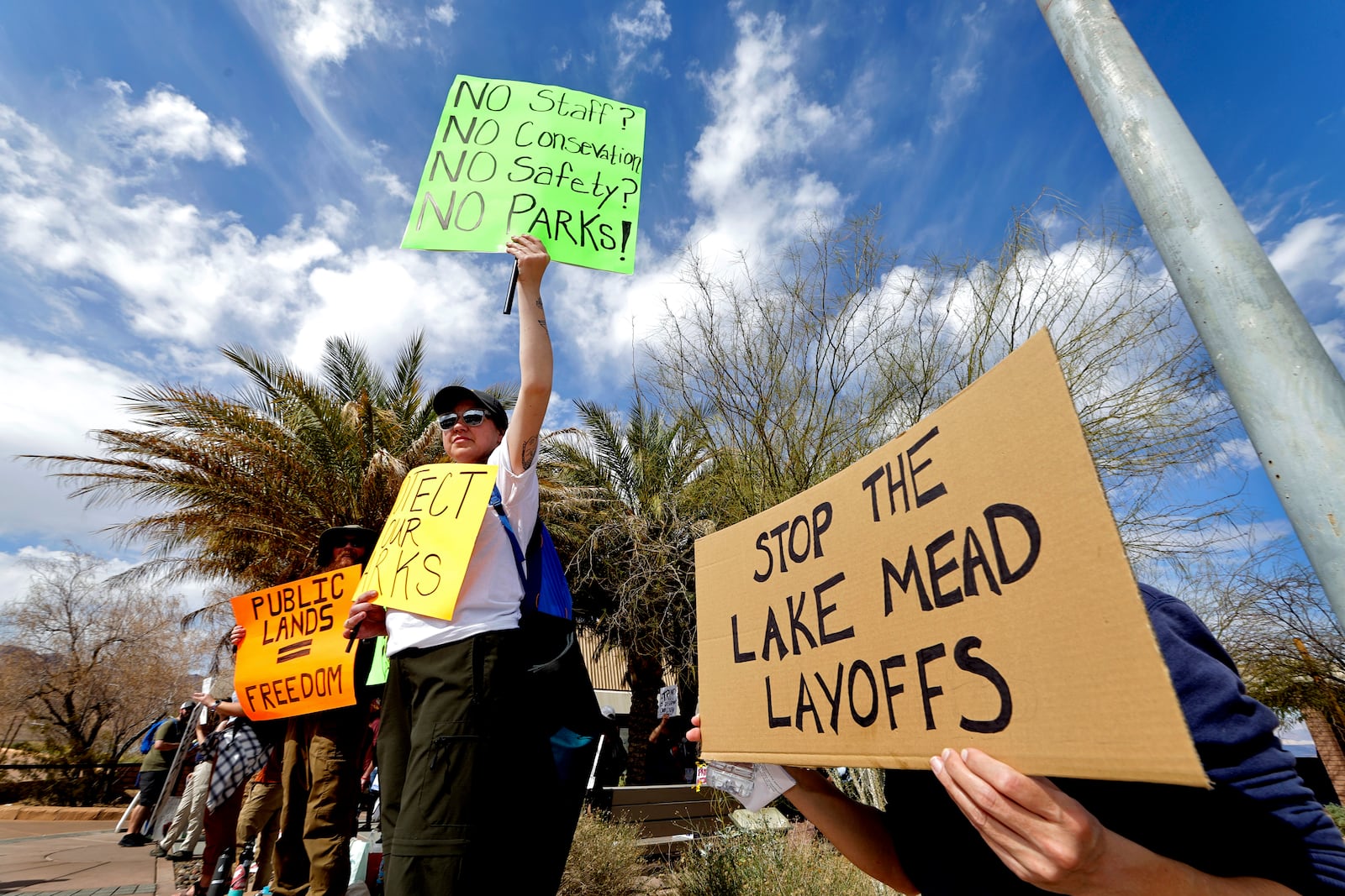 Jennifer Shoulders, center, of Las Vegas, holds up a sign during a "Protect Our Parks" rally, part of a national day of rallies to protest the layoffs of National Park Service employees, at the Lake Mead National Recreation Area Visitor Center Saturday, March 1, 2025, near Boulder City, Nev. (Steve Marcus/Las Vegas Sun via AP)