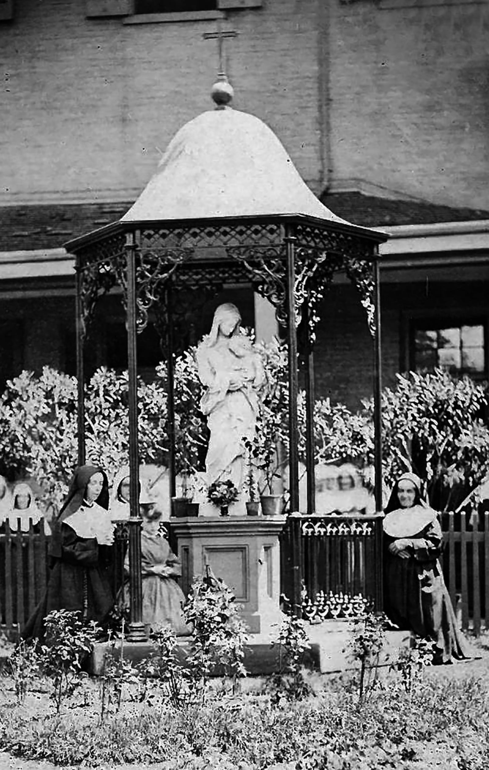 Sisters of Notre Dame de Namur gather at a statue of Virgin Mary in an undated photograph taken at Notre Dame Academy in Dayton. PHOTO COURTESY OF CHAMINADE JULIENNE CATHOLIC HIGH SCHOOL