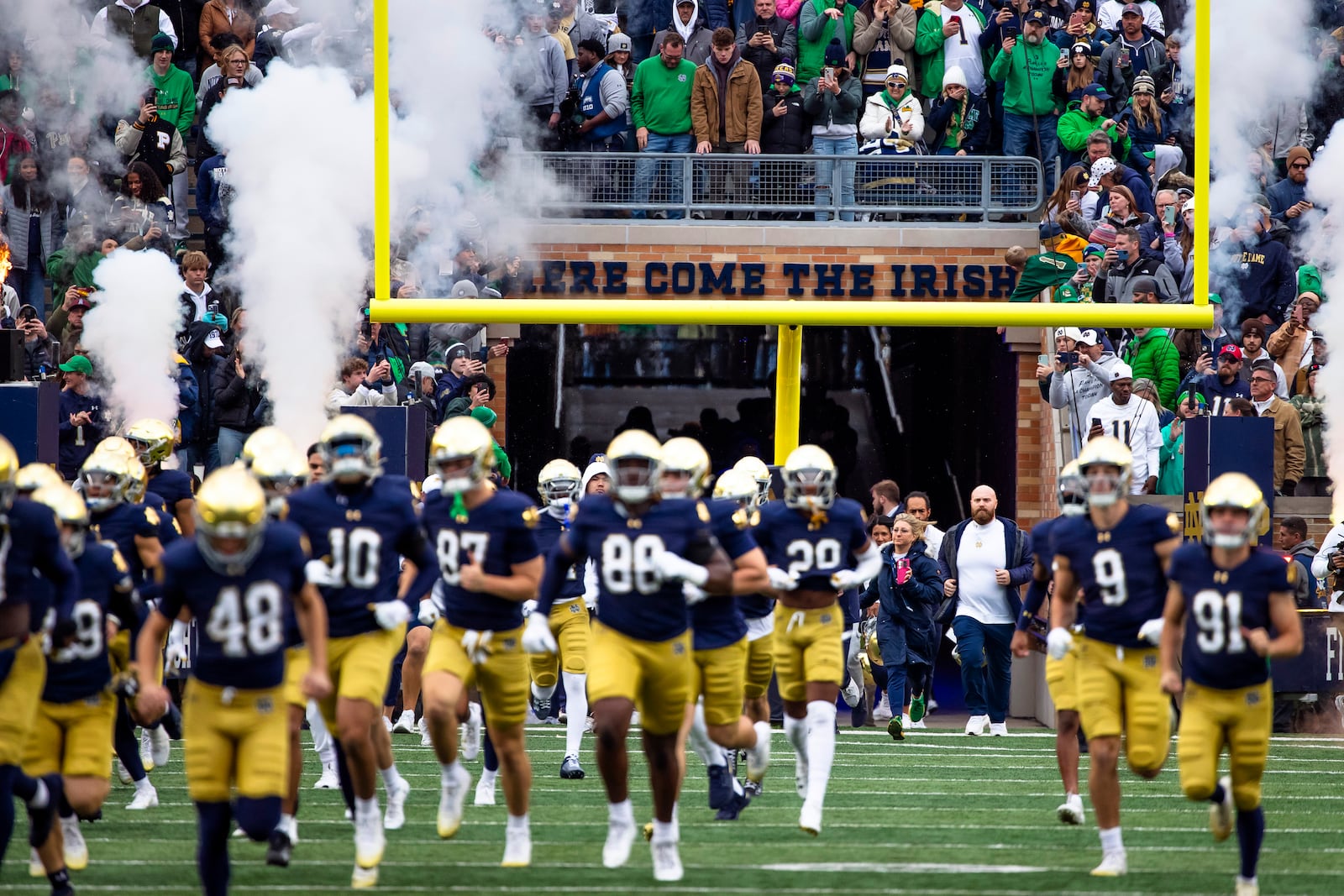 FILE - Notre Dame players run out from under the "Here Come The Irish" sign before the first half of an NCAA college football game against Virginia, Saturday, Nov. 16, 2024, in South Bend, Ind. (AP Photo/Michael Caterina, File)