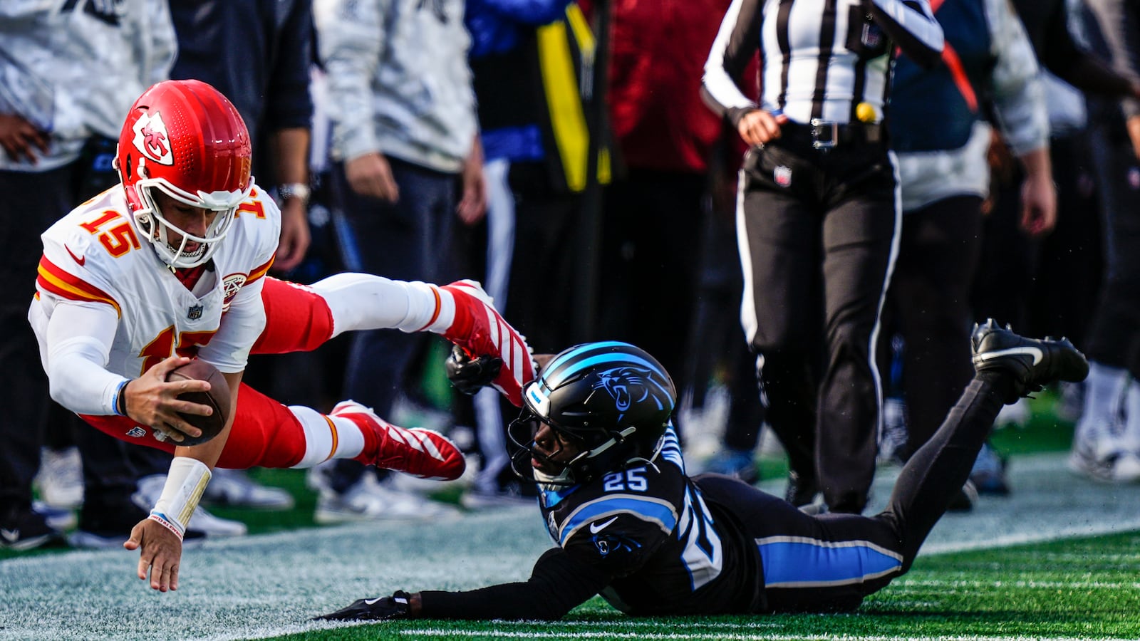 Kansas City Chiefs quarterback Patrick Mahomes (15) falls after a hit by Carolina Panthers safety Xavier Woods (25) during the first half of an NFL football game, Sunday, Nov. 24, 2024, in Charlotte, N.C. (AP Photo/Jacob Kupferman)