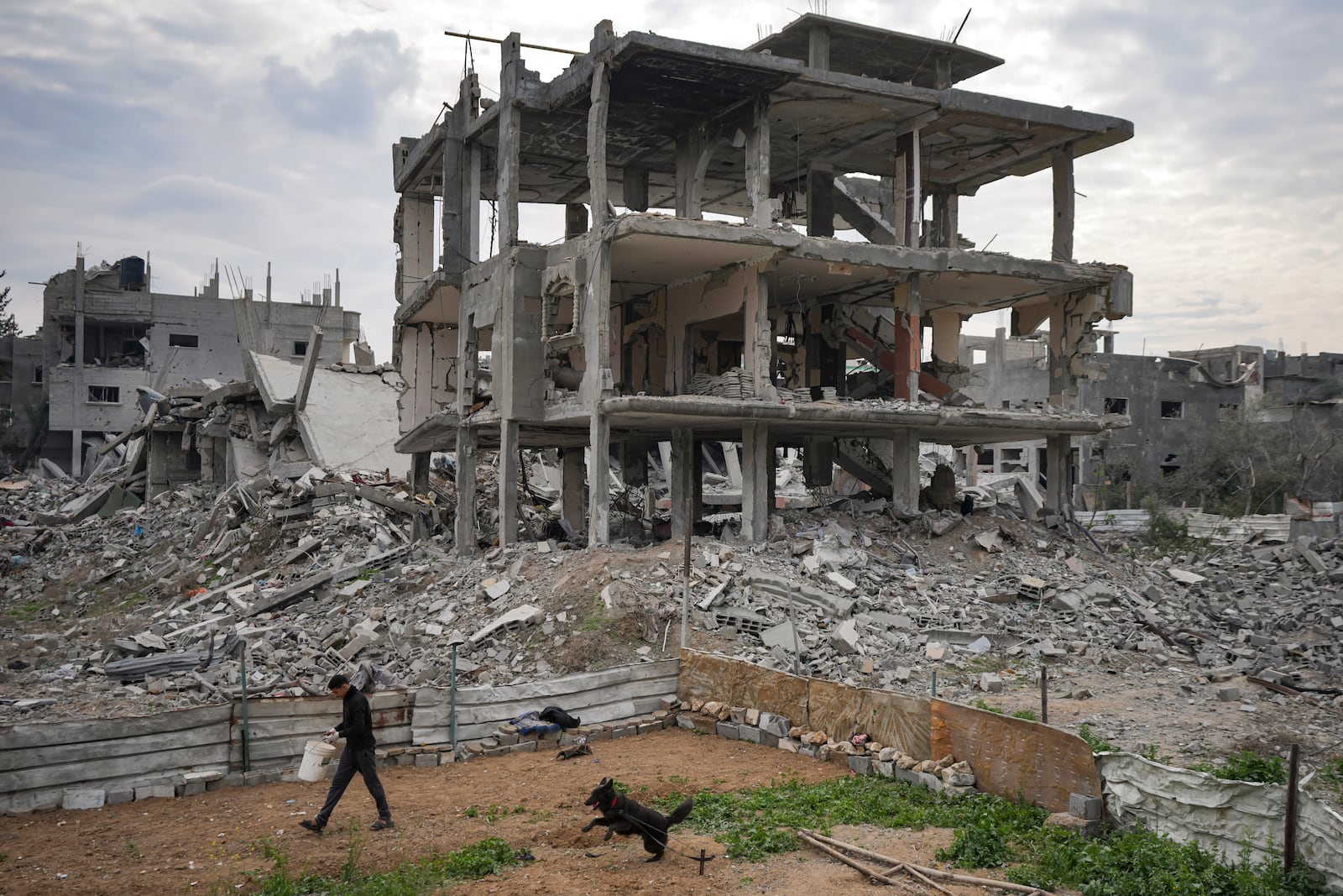 A Palestinian walks past destroyed residential buildings damaged by the Israeli air and ground offensive in Bureij, central Gaza Strip, Wednesday, Jan. 22, 2025. (AP Photo/Abdel Kareem Hana)