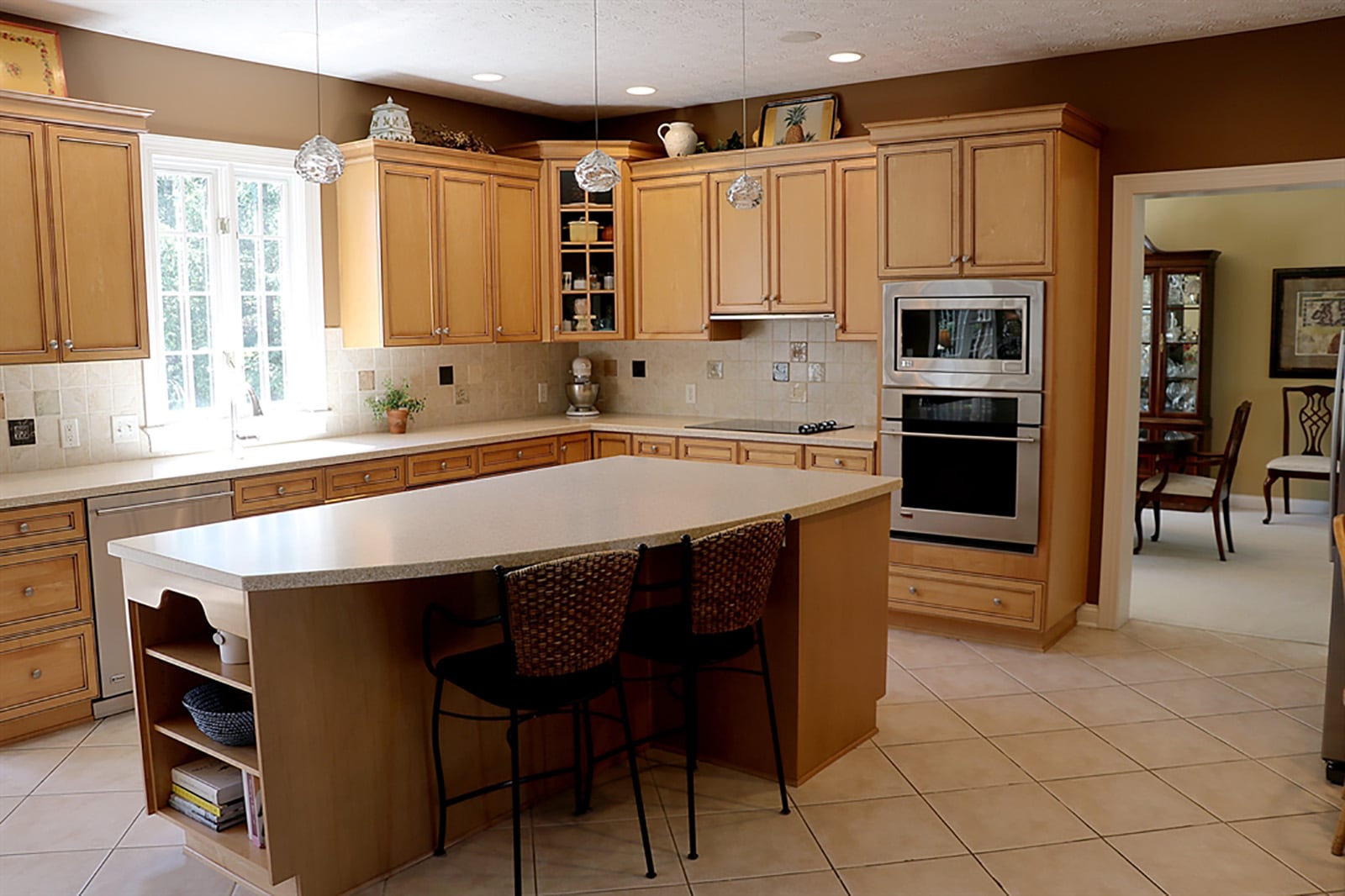 The kitchen features custom cabinetry of light wood with stained accents. The kitchen has light Corian and a color-accented, ceramic-tile backsplash. Corner cabinets have glass-panel doors, and open shelves are available at the end of the island that seats three and provides additional storage. CONTRIBUTED PHOTO BY KATHY TYLER