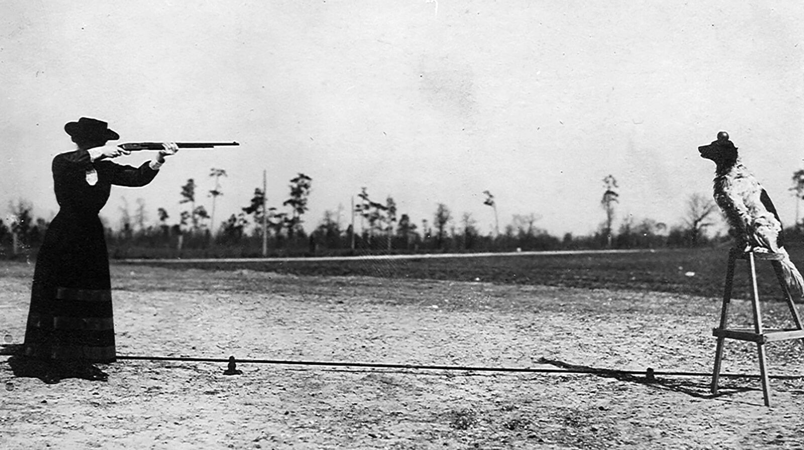 Annie Oakley takes aim at an apple sitting on top of her dog’s head. The English setter, named “Dave,” grew so accustomed to the sound of gunfire while hunting with Oakley and her husband Frank Butler that he became part of their show. PHOTO COURTESY OF THE NATIONAL ANNIE OAKLEY CENTER AT THE GARST MUSEUM