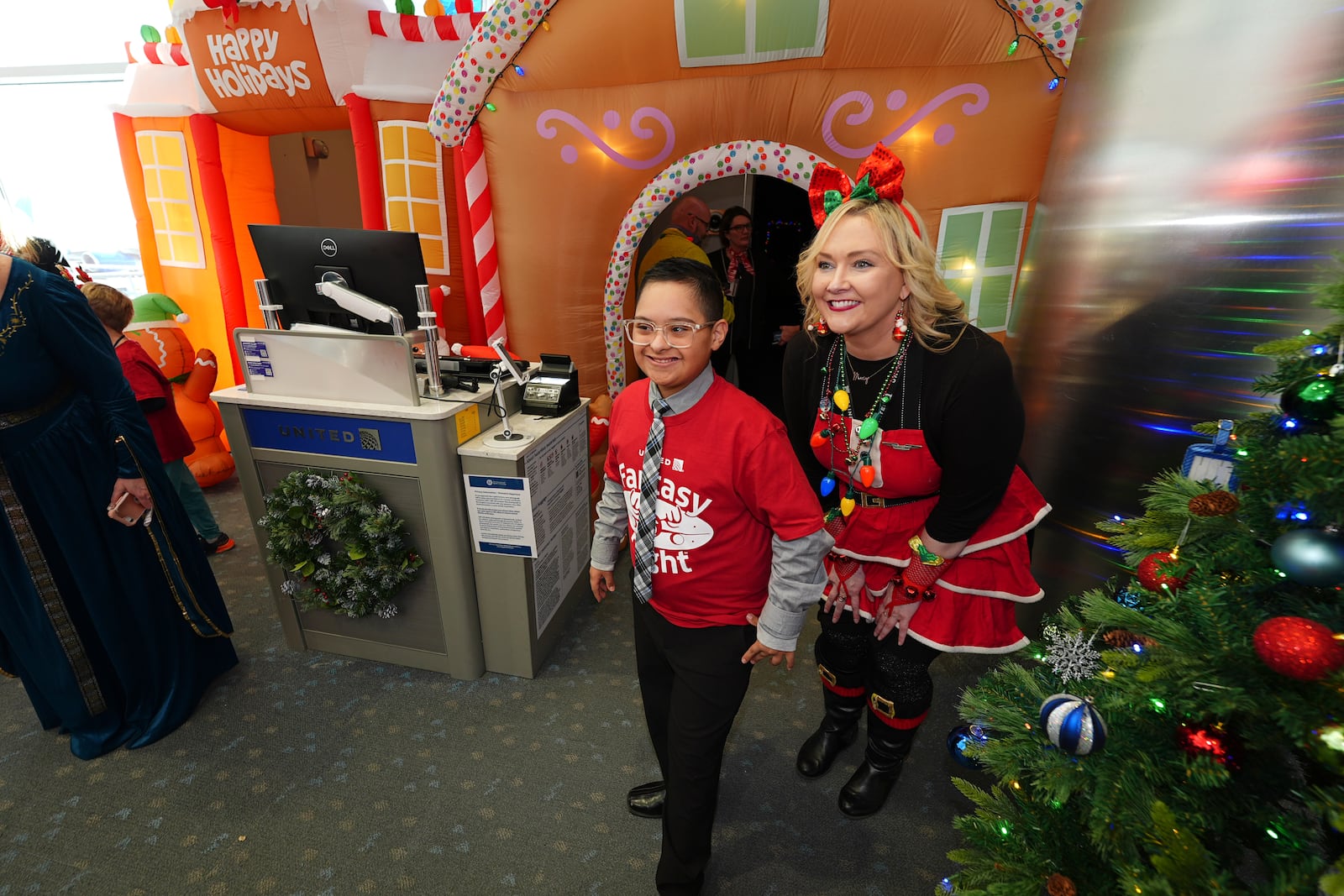 Twelve-year-old Adan Cervantes, left, waits to check in at the gate with the help of a flight attendant during the United Airlines annual "fantasy flight" to a fictional North Pole at Denver International Airport, Saturday, Dec. 14, 2024, in Denver. (AP Photo/David Zalubowski)