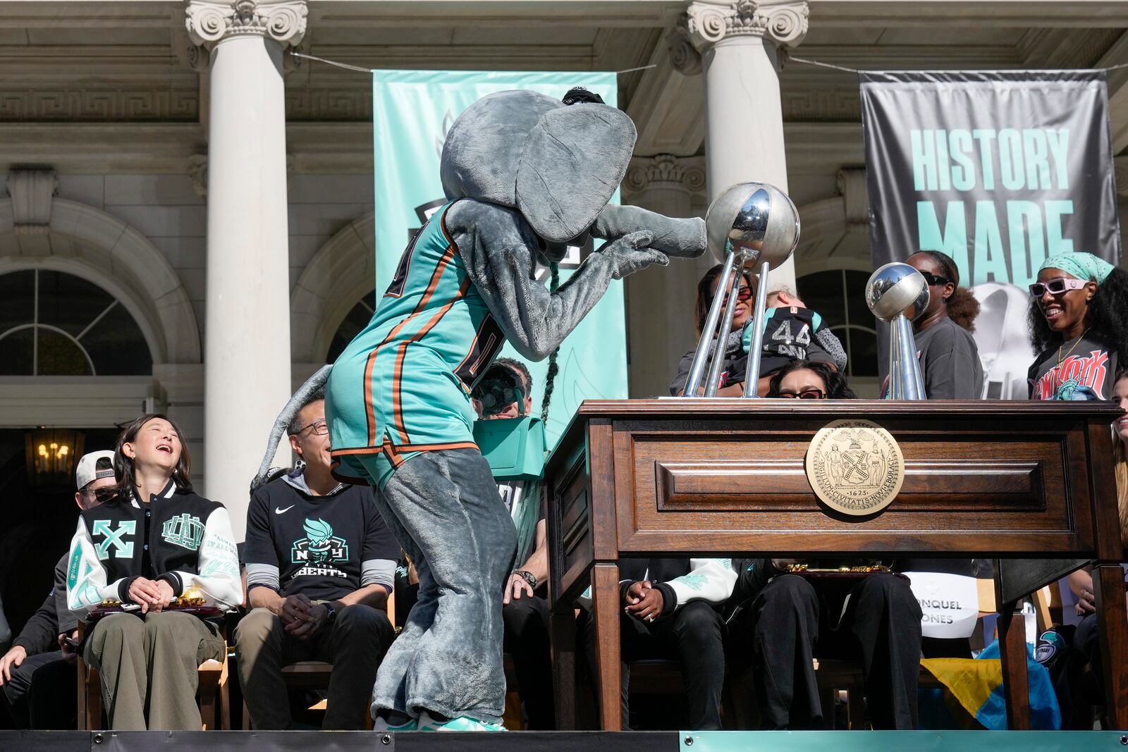 The New York Liberty mascot, Ellie the Elephant, kisses the championship trophy during a ceremony after a parade in honor of the Liberty's WNBA basketball championship at City Hall in New York, Thursday, Oct. 24, 2024. (AP Photo/Seth Wenig)