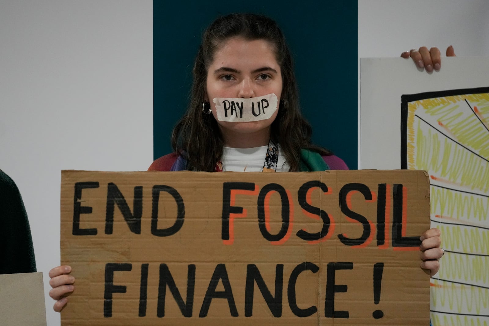 A demonstrator holds a sign that reads "end fossil finance!" at the COP29 U.N. Climate Summit, Saturday, Nov. 23, 2024, in Baku, Azerbaijan. (AP Photo/Rafiq Maqbool)