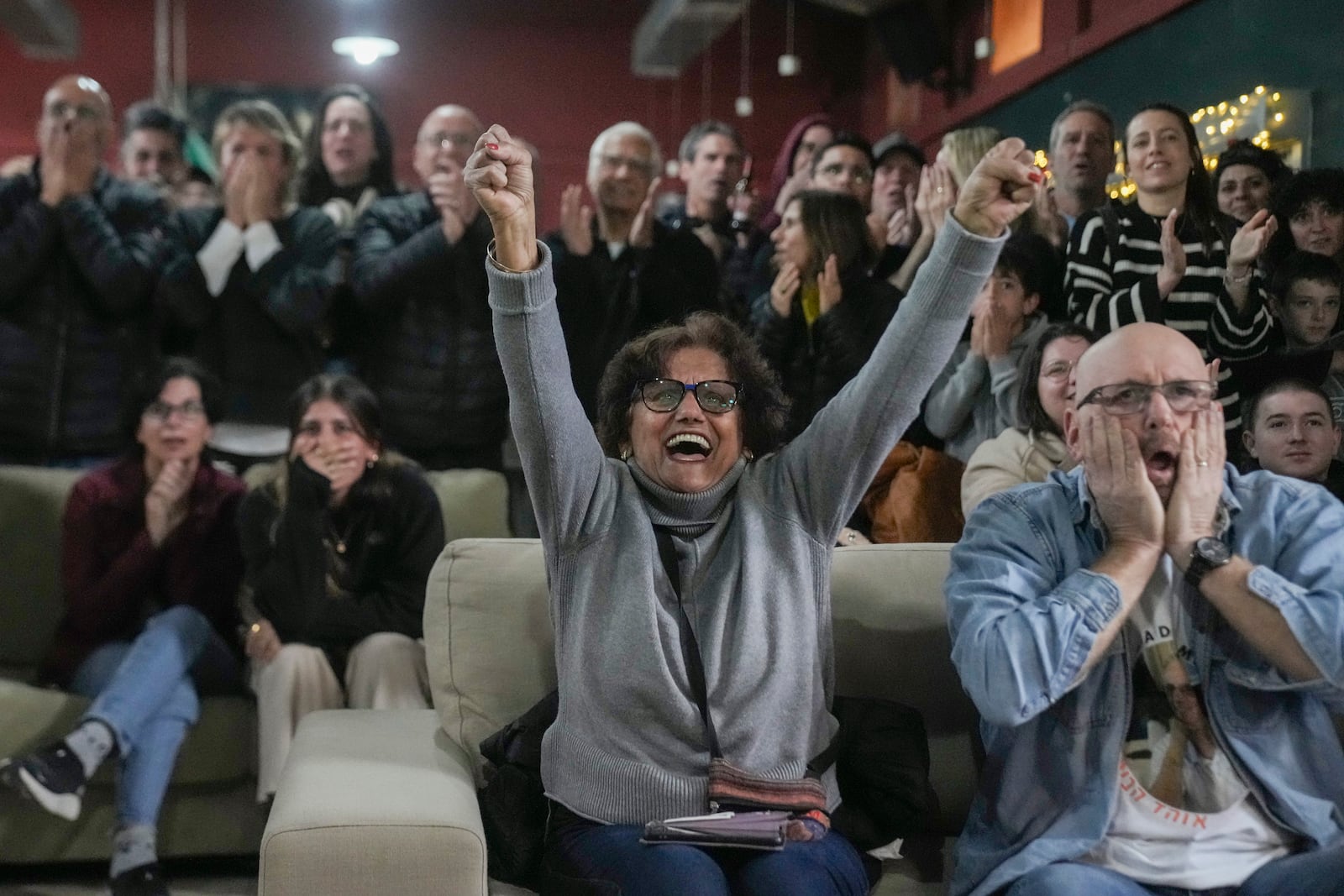 Friends and relatives of Ohad Ben Ami and Eli Sharabi, who were taken from kibbutz Beeri on Oct.7, 2023 attack, react as they watch the live broadcast of their release from Hamas captivity in Gaza, at the Kibbutz Beeri, Israel, Saturday, Feb. 8, 2025, as part of the Israel-Hamas ceasefire deal. (AP Photo/Maya Alleruzzo)