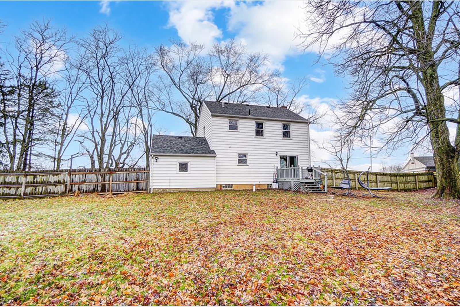 The rear of the property features a fully fenced backyard and a wood deck with railings. There is also a yard building.