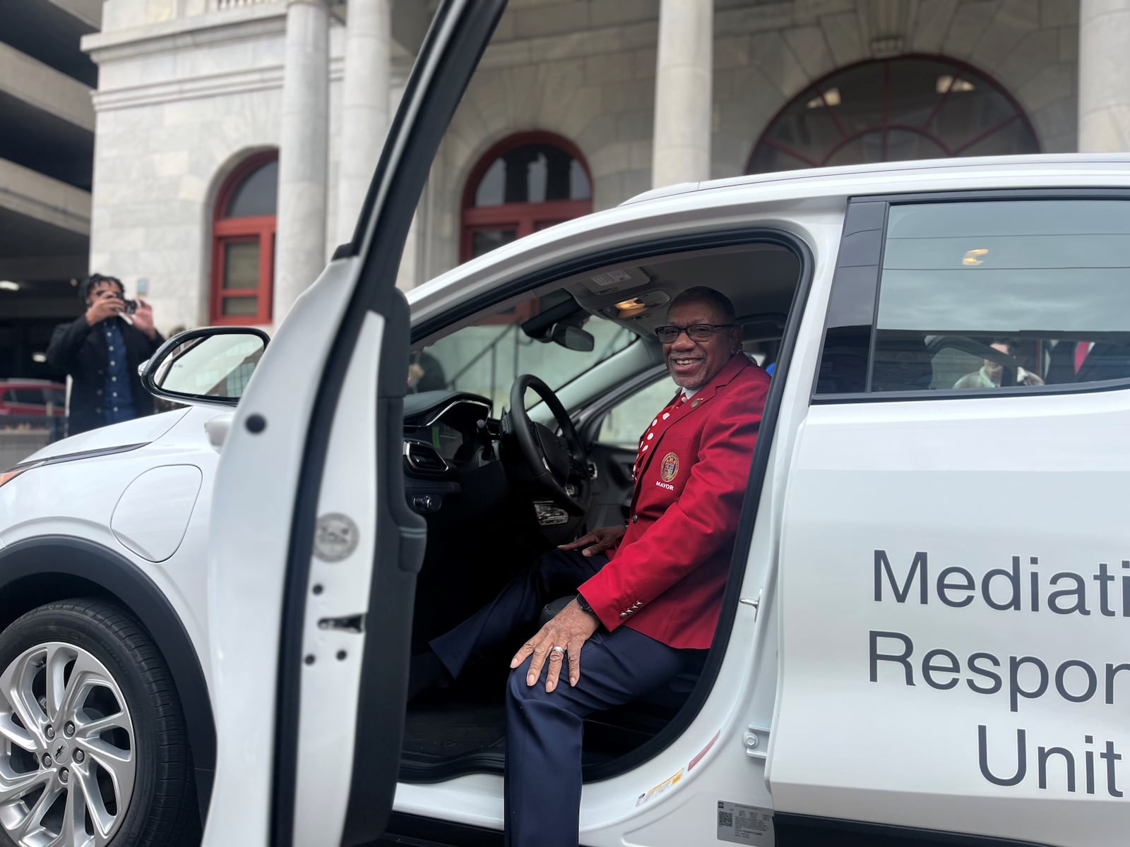 Dayton Mayor Jeffrey Mims Jr. sits in one of the five Chevrolet Bolts the city has acquired, which are the city's first all-electric vehicles. CORNELIUS FROLIK / STAFF