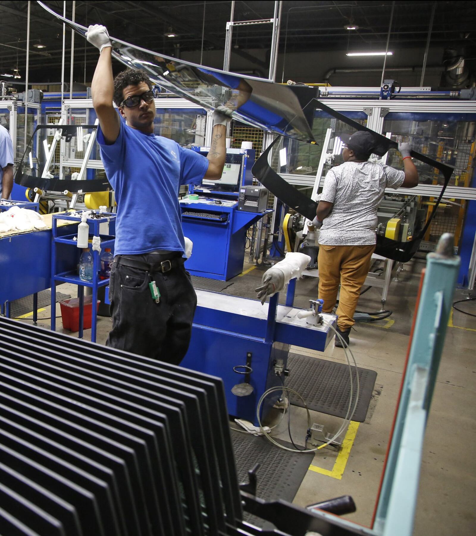 Workers at Fuyao Glass America finish an automobile windshield in the Moraine plant. Fuyao currently employs 2,300 workers and expects to need another 700 more within 3 years. TY GREENLEES / STAFF