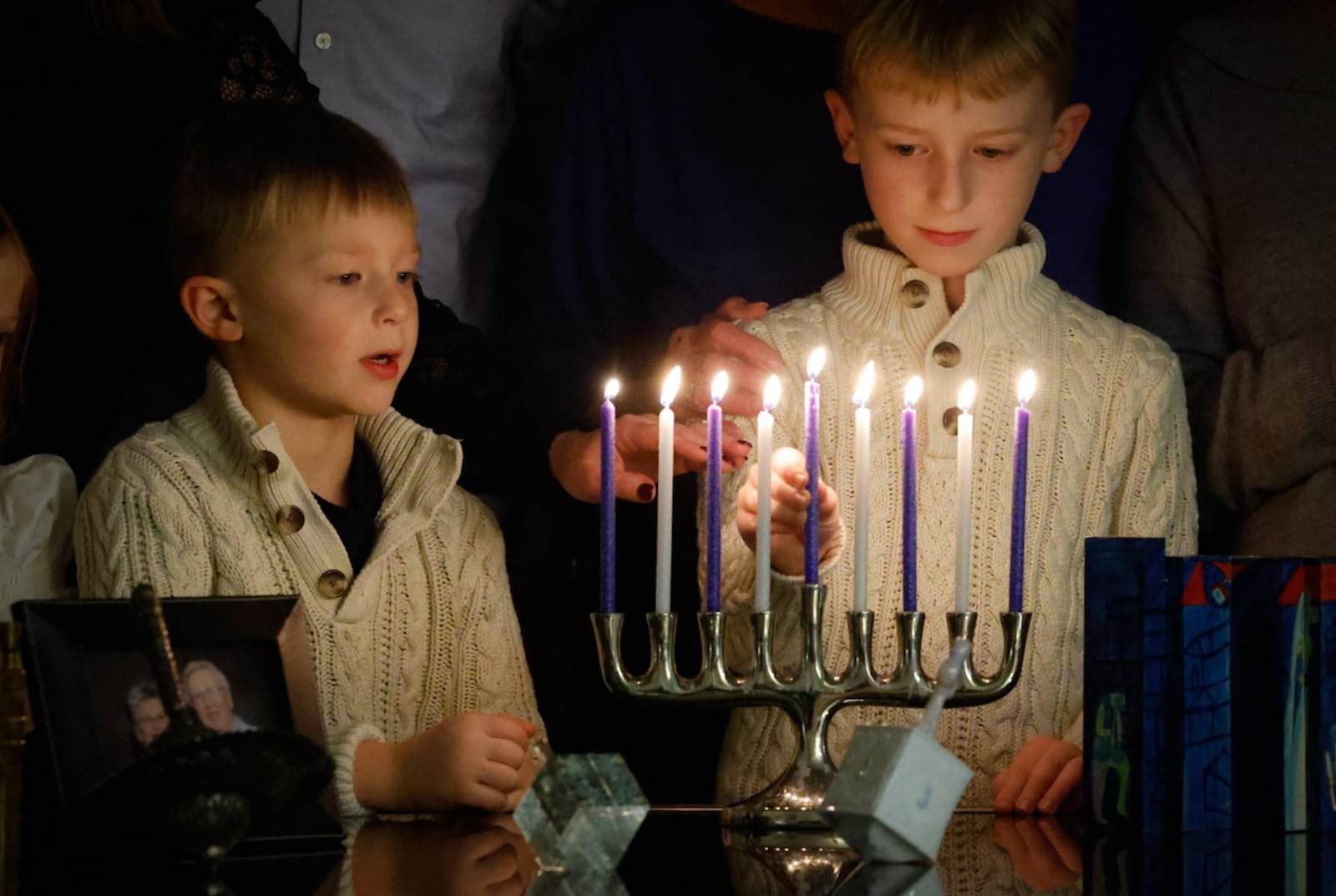 Parker Sweeny left and his brother Leyton Sweeny light the menorah together. JIM NOELKER/STAFF