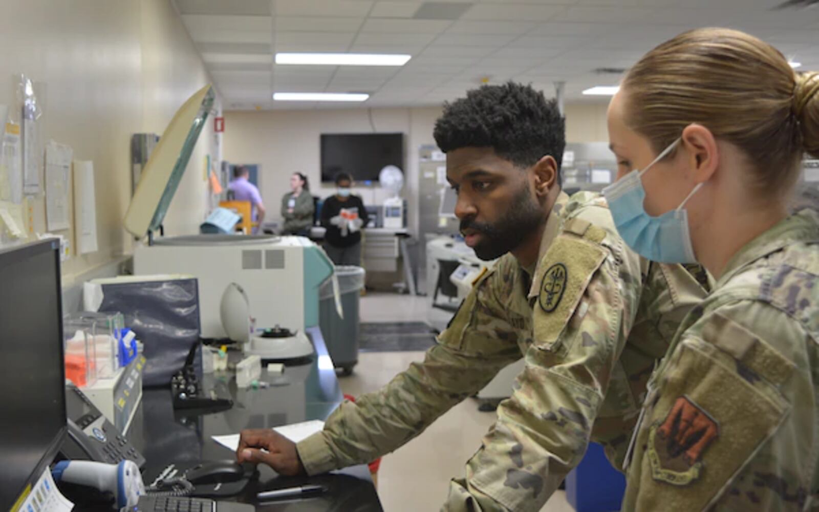 Sgt. Bruce Mayo, medical laboratory technician, and Tech. Sgt. Melissa Lambert, medical laboratory technician, from Nellis Air Force Base input laboratory results into the new MHS Genesis system during the first day of the launch of the new system at Carl R. Darnall Army Medical Center in March 2022. (U.S. Army photo by Rodney Jackson, CRDAMC Public Affairs)