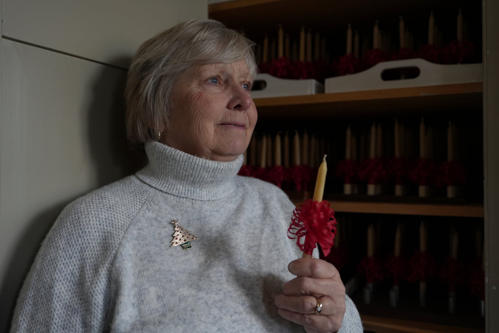 Central Moravian Church member Linda Thudium walked holds one of the thousands of handmade beeswax candles that her congregation will light during a Christmas service as part of a Moravian tradition in in Bethlehem, Pa., on Sunday, Dec. 1, 2024. (AP Photo/Luis Andres Henao)