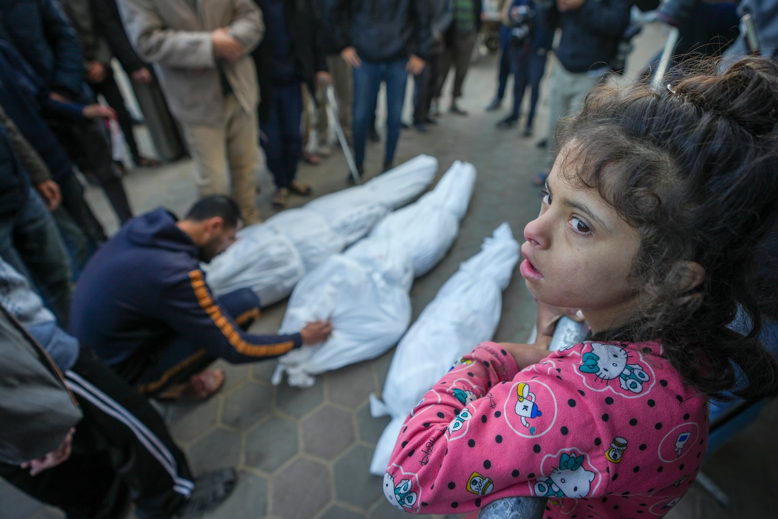 A girl watches as Mohammad Eid mourns his daughter Dima, along with her uncle and grandfather, who were killed in an Israeli airstrike on Saturday, during their funeral in Deir al-Balah, central Gaza Strip, Sunday, Jan. 12, 2025. (AP Photo/Abdel Kareem Hana)