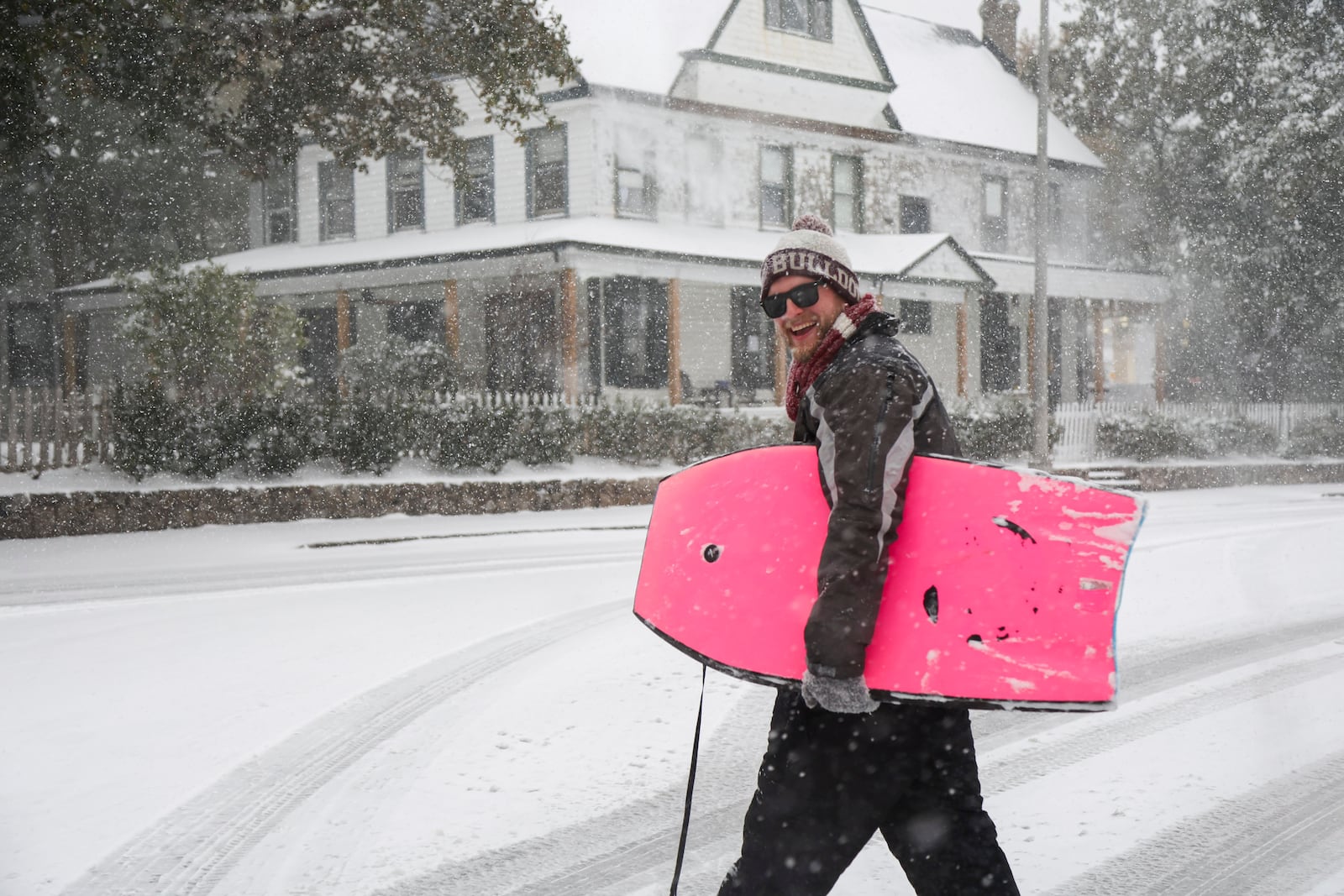 Luke Marshall walks down snow covered streets with a body board on Tuesday, Jan. 21, 2025, in Pensacola, Fla. (Luis Santana/Tampa Bay Times via AP)