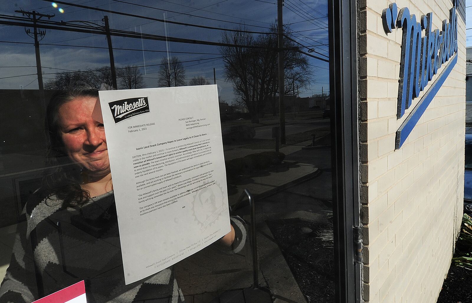 An employee of Mikesell's Potato Chips posts a letter onto the front door of the business Wednesday, Feb. 1, 2023, announcing that they will be closing operations in Dayton after 110 years. MARSHALL GORBY/STAFF