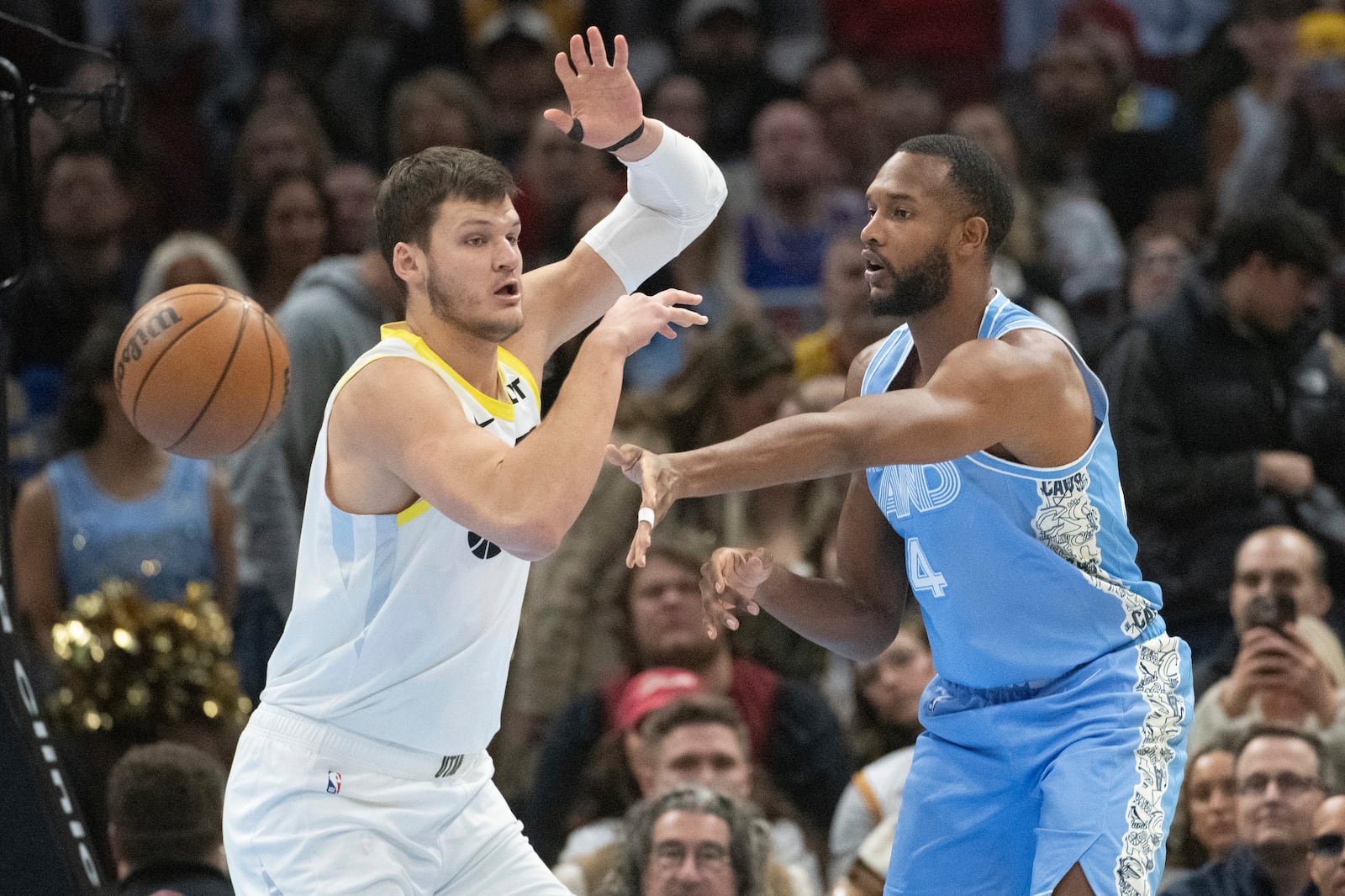 Cleveland Cavaliers' Evan Mobley, right, passes around Utah Jazz' Walker Kessler during the first half of an NBA basketball game in Cleveland, Monday, Dec. 23, 2024. (AP Photo/Phil Long)