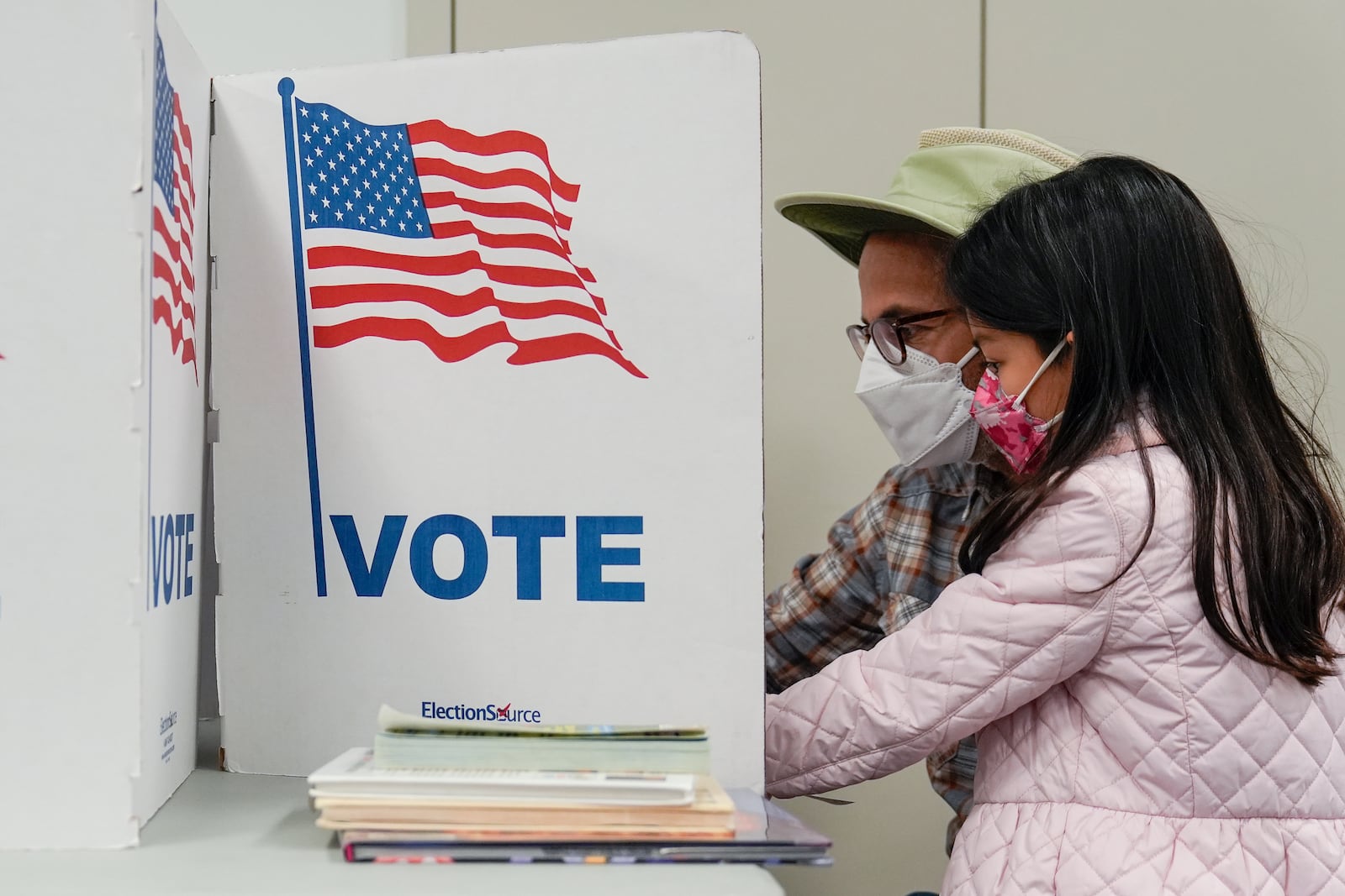 A person marks their ballot as their child looks on at the polling place at Tysons-Pimmit Regional Library in Falls Church, Va., Thursday, Oct. 31, 2024. (AP Photo/Stephanie Scarbrough)