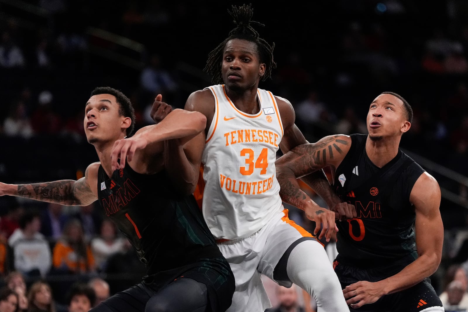 Miami center Lynn Kidd (1), left, and guard Matthew Cleveland (0), right, guard Tennessee forward Felix Okpara (34), center, during the first half of an NCAA college basketball game, Tuesday, Dec. 10, 2024, in New York. (AP Photo/Julia Demaree Nikhinson)