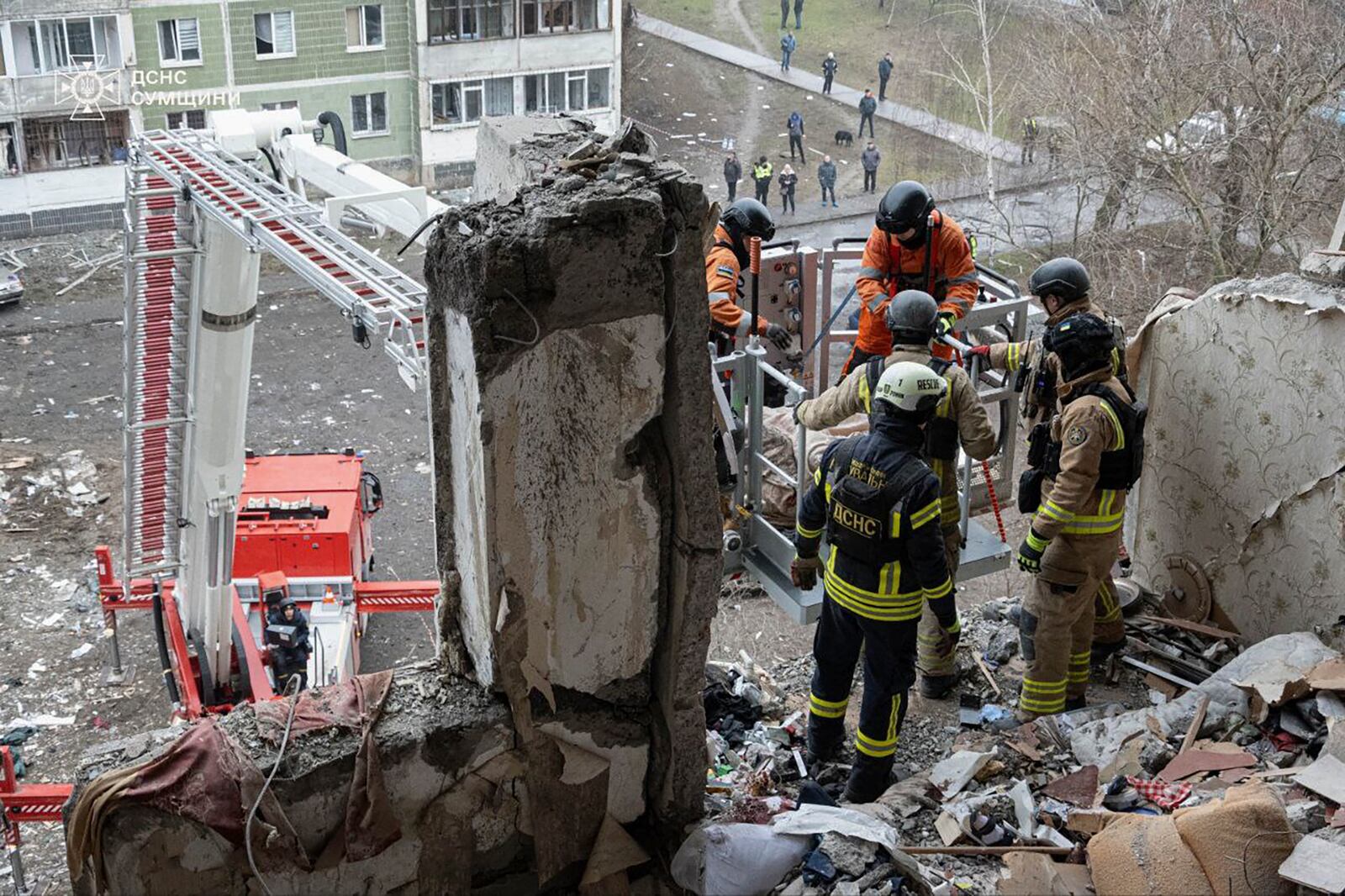 In this photo provided by the Ukrainian Emergency Service, rescuers search for civilians who were killed when a Russian drone hit an apartment building in Sumy, Ukraine, Thursday, Jan. 30, 2025. (Ukrainian Emergency Service via AP)