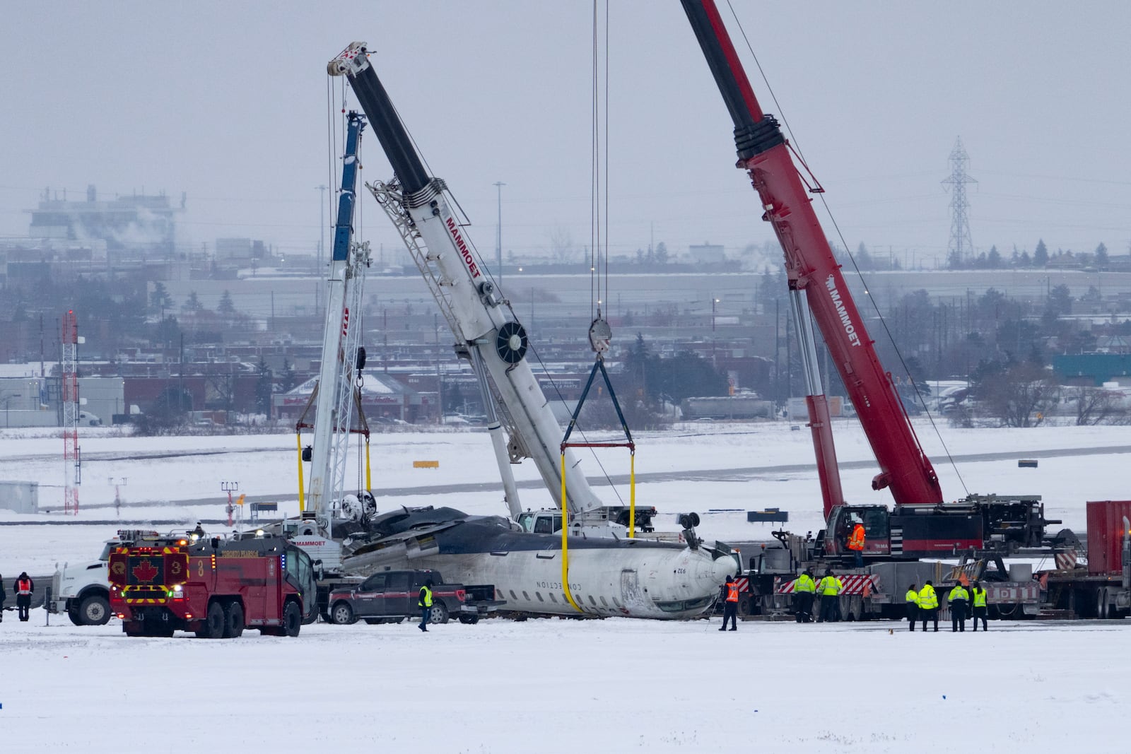 Cranes are positioned to remove the wreckage of Delta Flight 4819 from the runway at Toronto Pearson International Airport, in Mississauga, Ontario, on Wednesday, Feb. 19, 2025. (Arlyn McAdorey/The Canadian Press via AP)