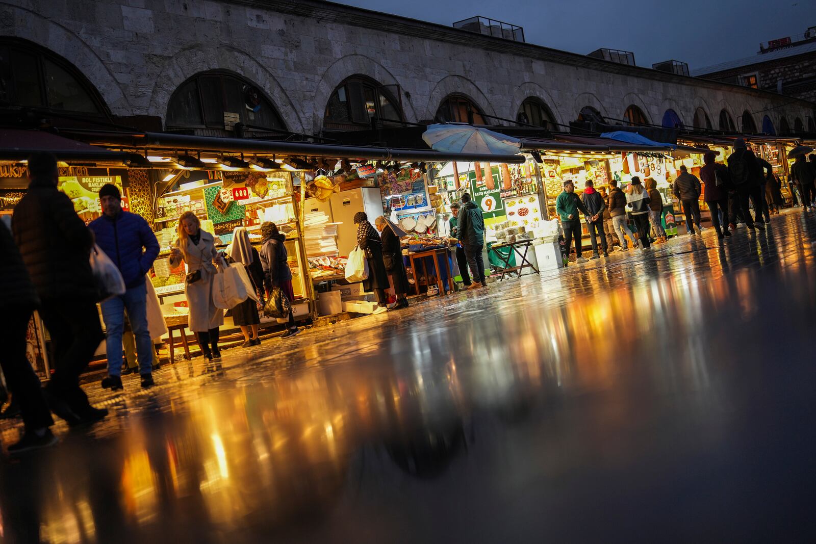 People buy food outside the Egyptian market at Eminonu commercial area, in Istanbul, Turkey, Thursday, Dec. 26, 2024, as Turkey's central bank lowered its key interest rate by 2.5 percentage points to 47.5% carrying out its first rate cut in nearly two years as it tries to control soaring inflation. (AP Photo/Francisco Seco)