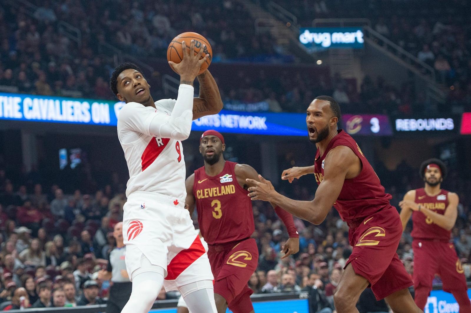 Toronto Raptors' RJ Barrett, left, grabs the ball as Cleveland Cavaliers' Evan Mobley, front left, reacts and Caris LeVert (3) watches during the first half of an NBA basketball game in Cleveland, Thursday, Jan. 9, 2025. (AP Photo/Phil Long)