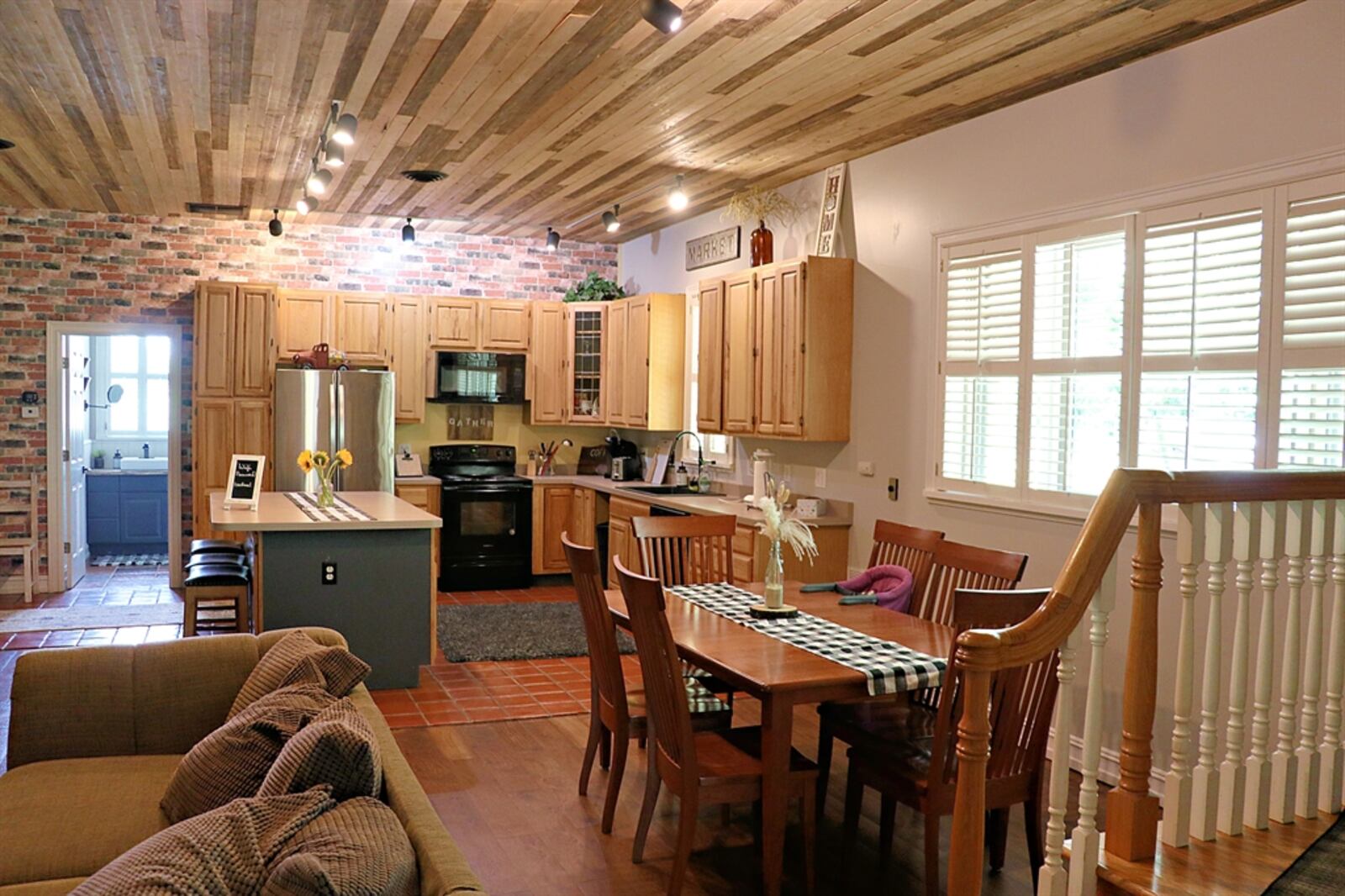 Attached to the barn is a 1,080-square-foot guesthouse, which is currently being used as an Airbnb. The guesthouse has an open-concept floor plan with a combined living room and kitchen with island under a repurposed wood plank paneled ceiling. 