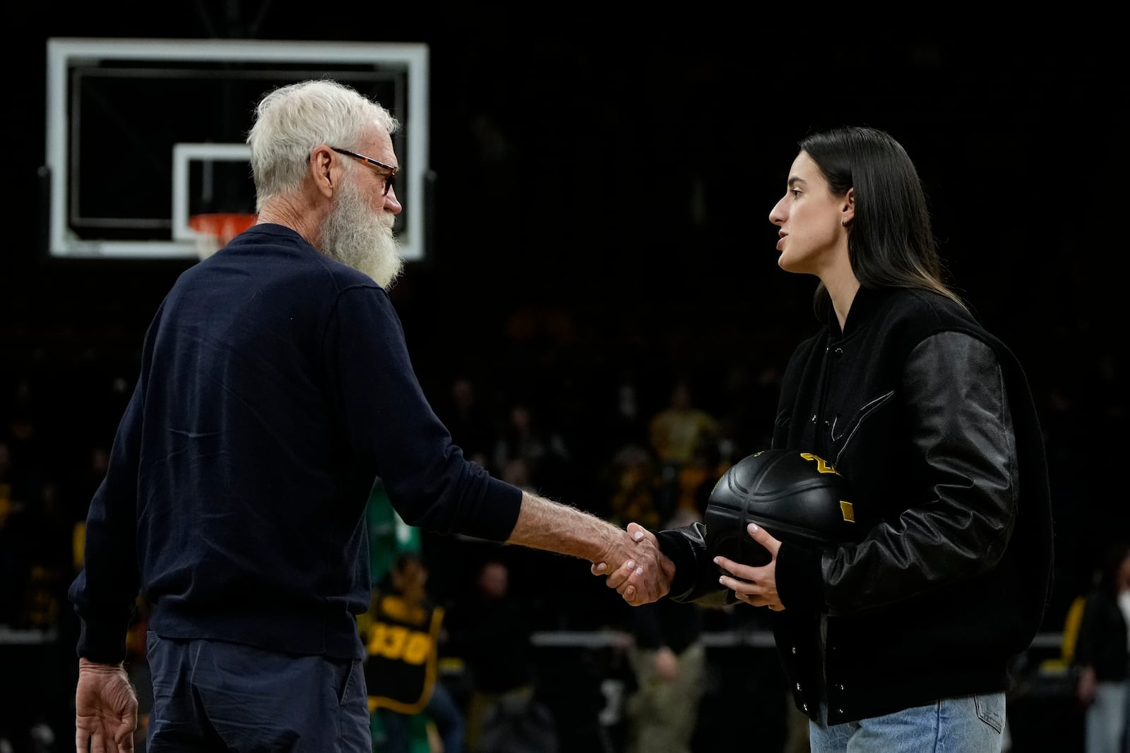 Former Iowa guard and current Indiana Fever WNBA player Caitlin Clark, right, greets David Letterman, left, during her jersey retirement ceremony after an NCAA college basketball game between Iowa and Southern California, Sunday, Feb. 2, 2025, in Iowa City, Iowa. (AP Photo/Charlie Neibergall)