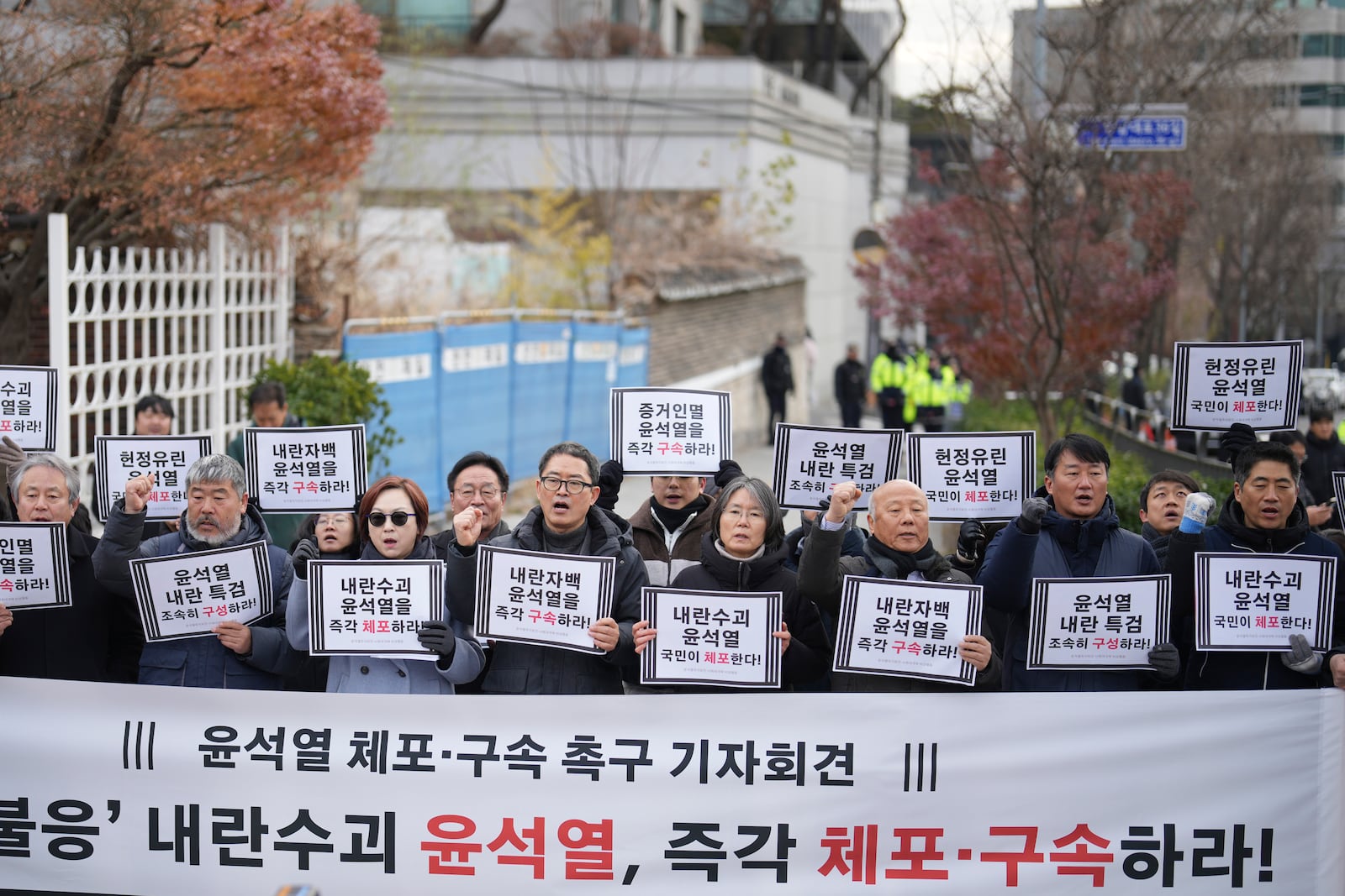 Members of civic groups shout slogans during a news conference demanding the arrest of President Yoon Suk Yeol near the presidential residence in Seoul, South Korea, Tuesday, Dec. 17, 2024. The letters read "Immediately arrest Yoon Suk Yeol." (AP Photo/Lee Jin-man)